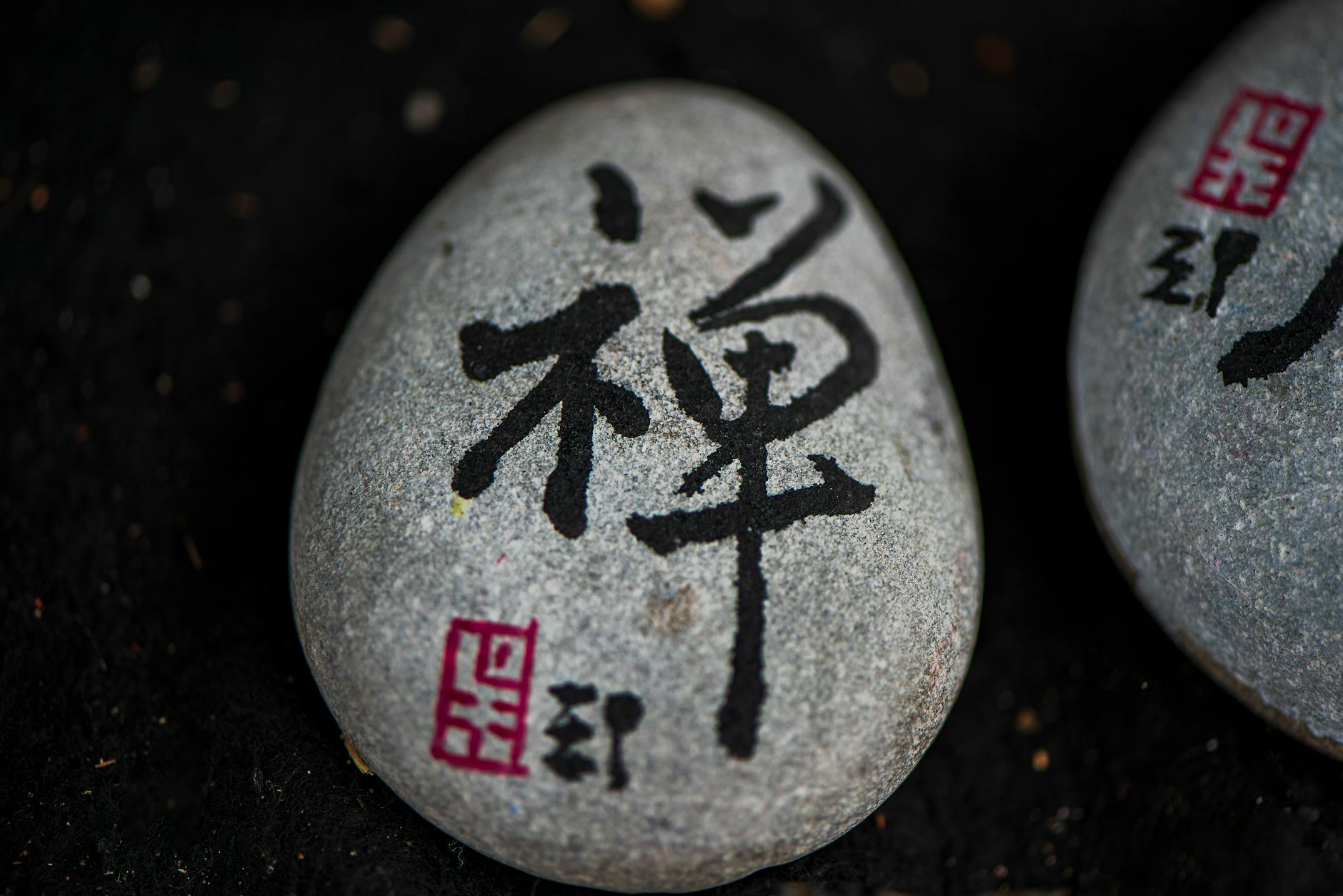 Close-up of a stone with Japanese calligraphy symbolizing zen and tranquility.