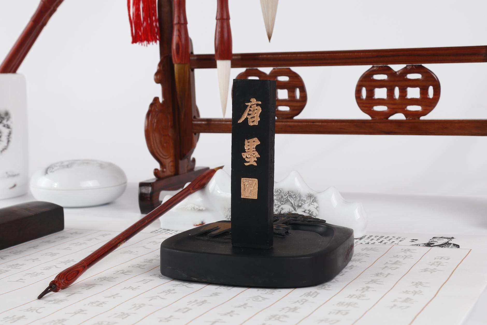 Elegant display of Chinese calligraphy tools including brushes, ink stick, and holder on a scroll.