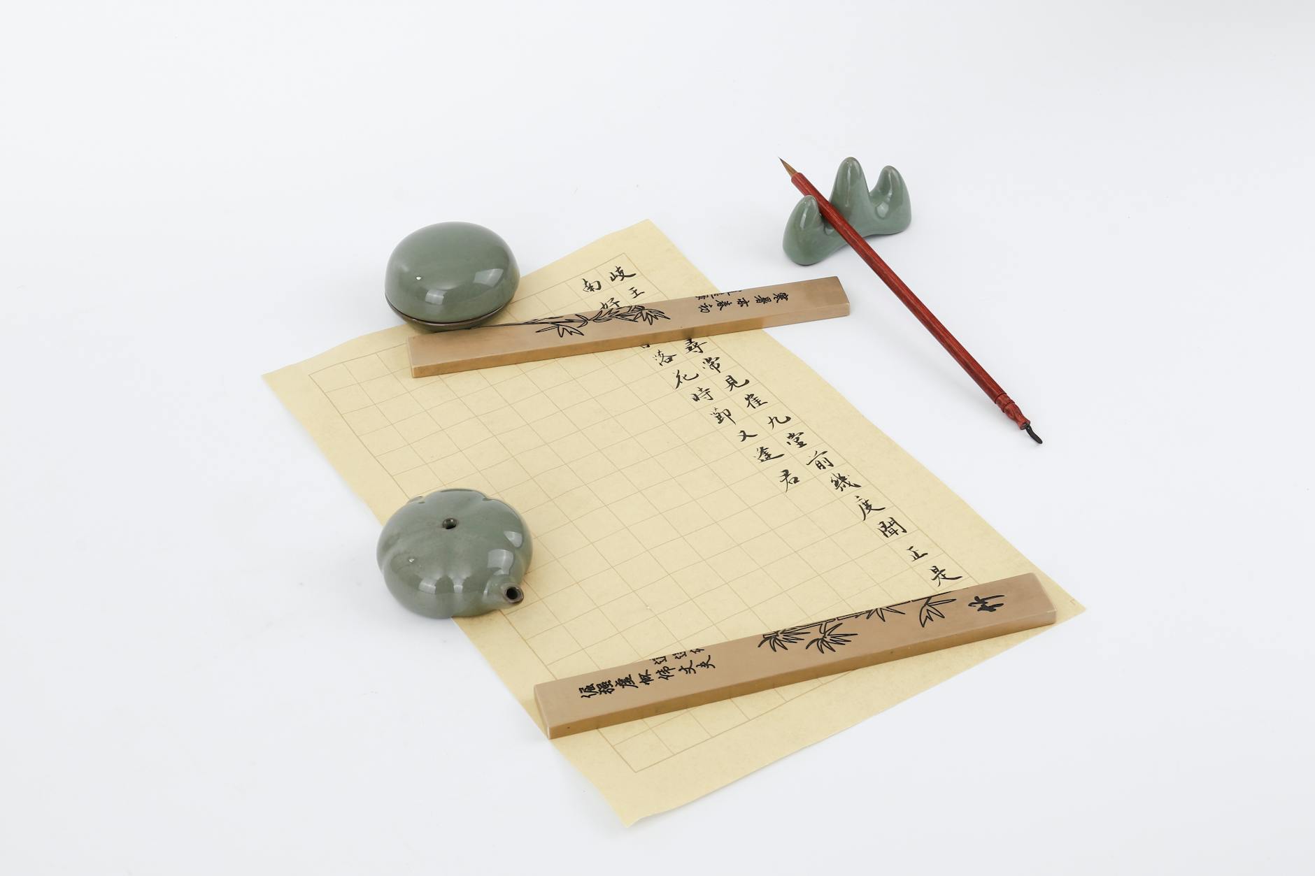 Flat lay of a traditional Chinese calligraphy set with brush, paper, and ink stones on a white background.