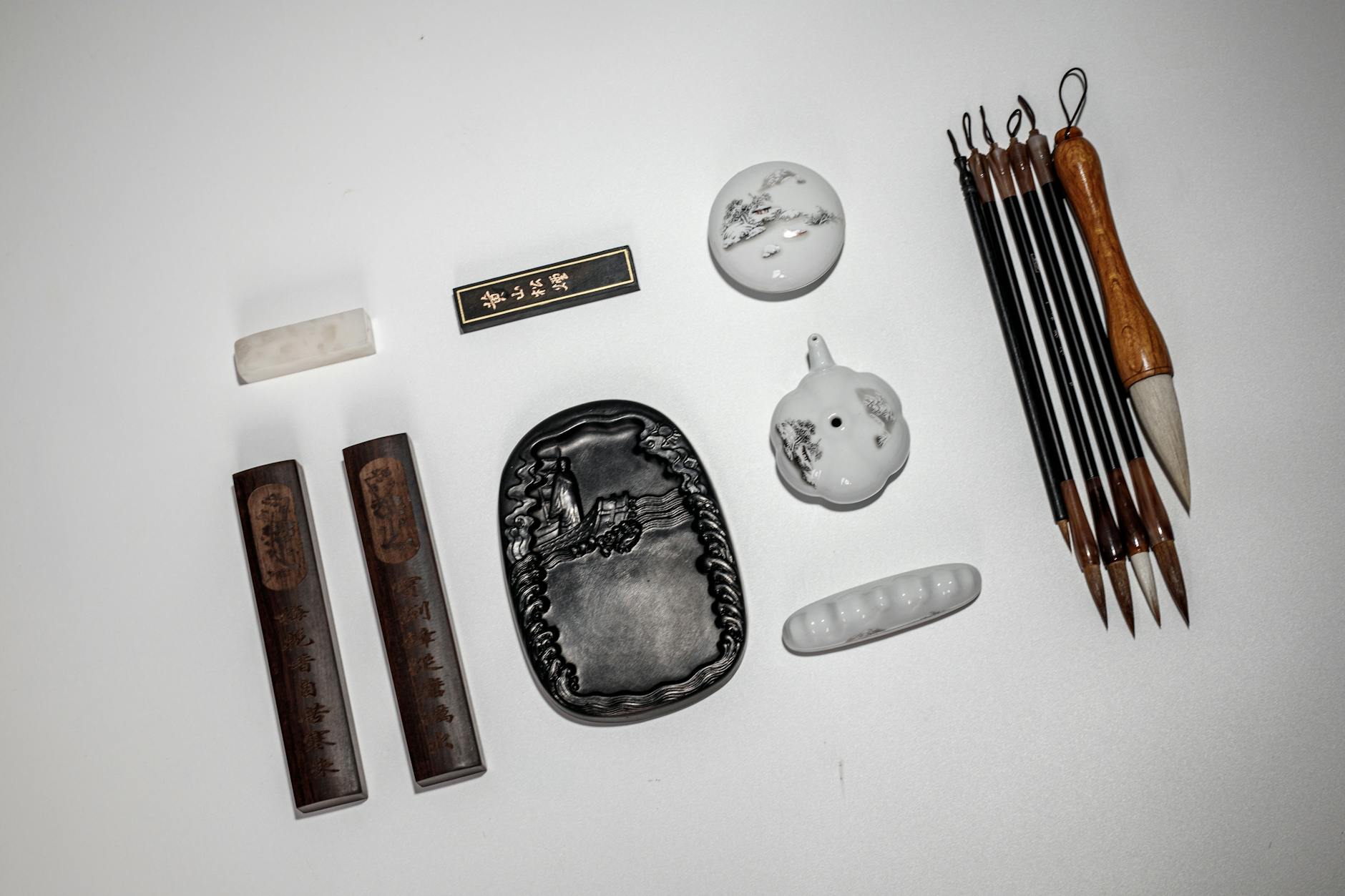 Flat lay of traditional Chinese calligraphy tools including ink stone, brushes, and ink sticks.
