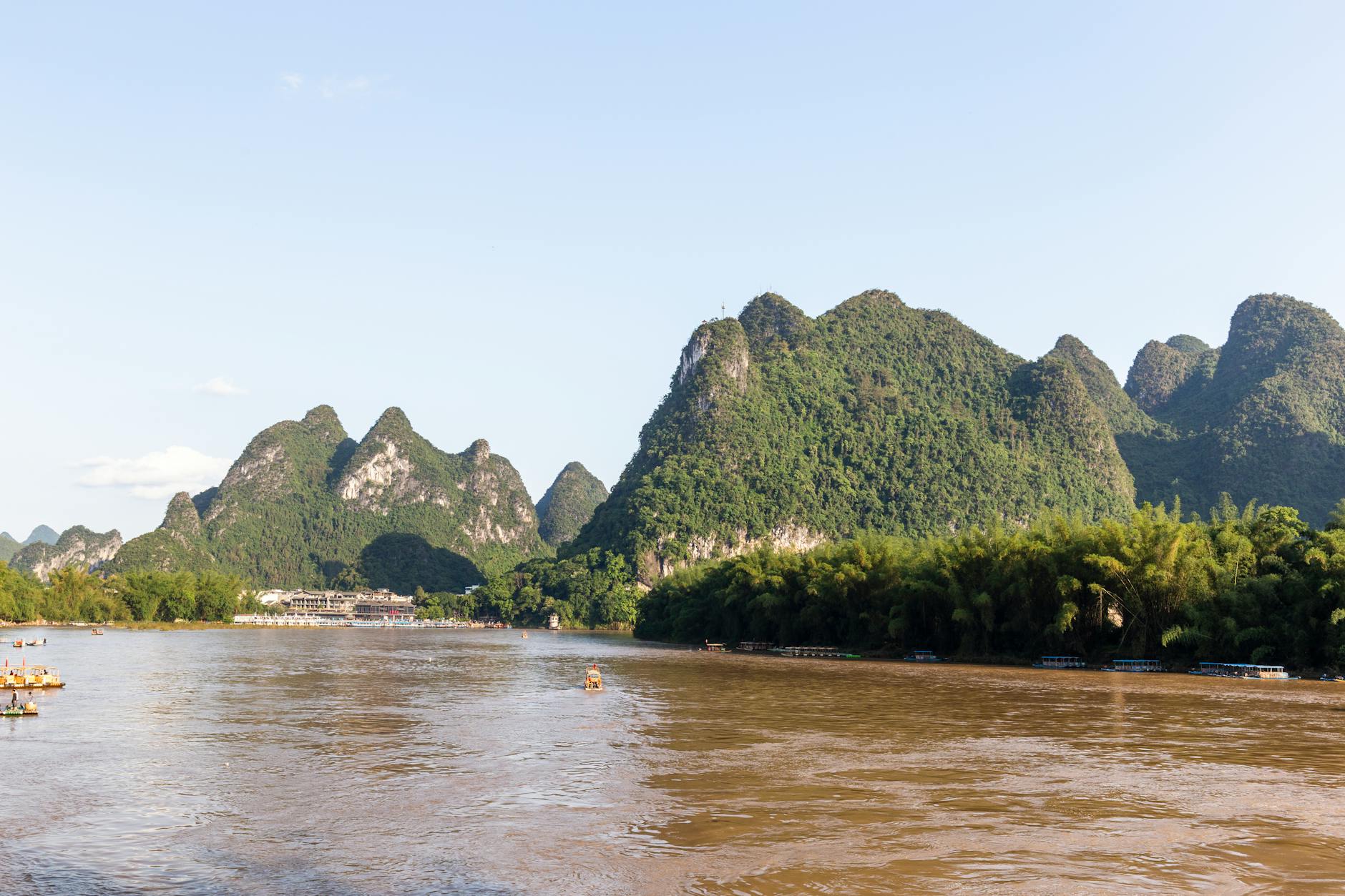 A serene landscape of karst mountains and the Li River in Guilin, China, under a clear sky.