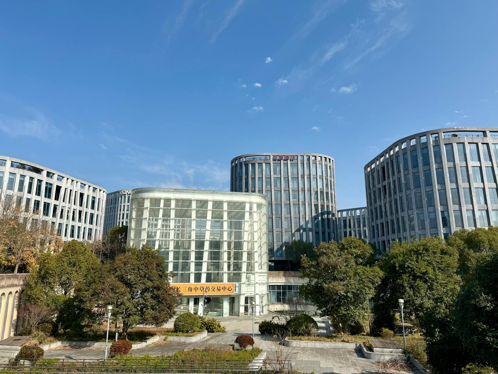 Contemporary office buildings framed by lush greenery in sunny Zhangjiang, Shanghai.