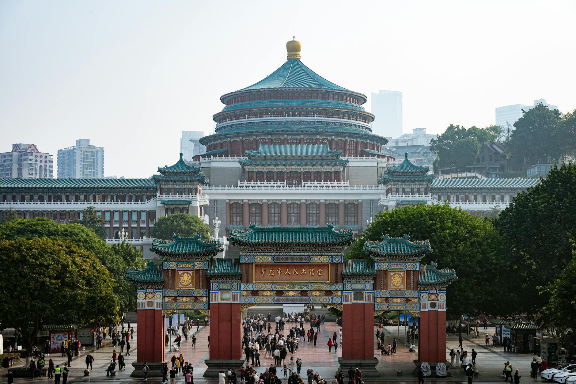 The majestic Chongqing Great Hall of the People with vibrant crowds below.