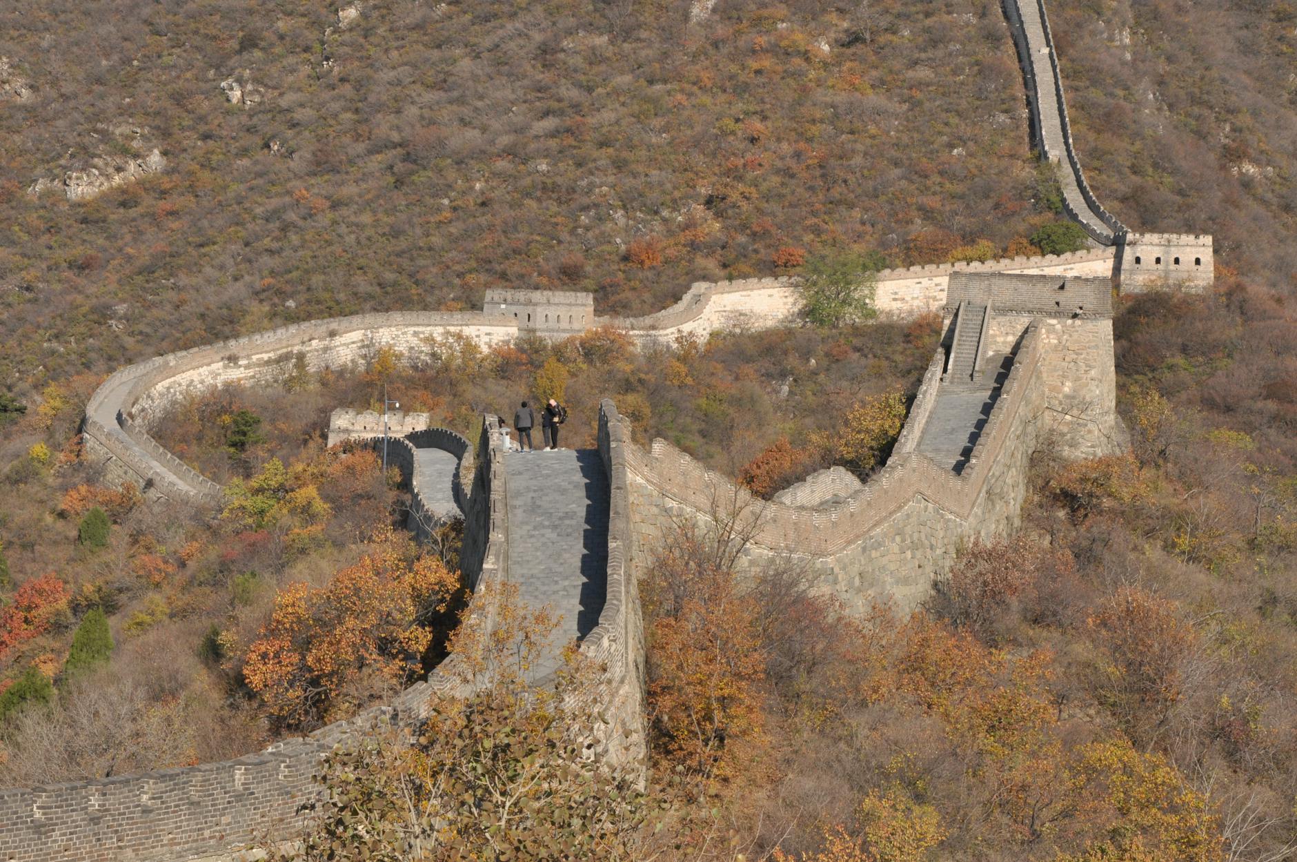 Aerial view of the Great Wall of China with autumn foliage, showcasing historical architecture.