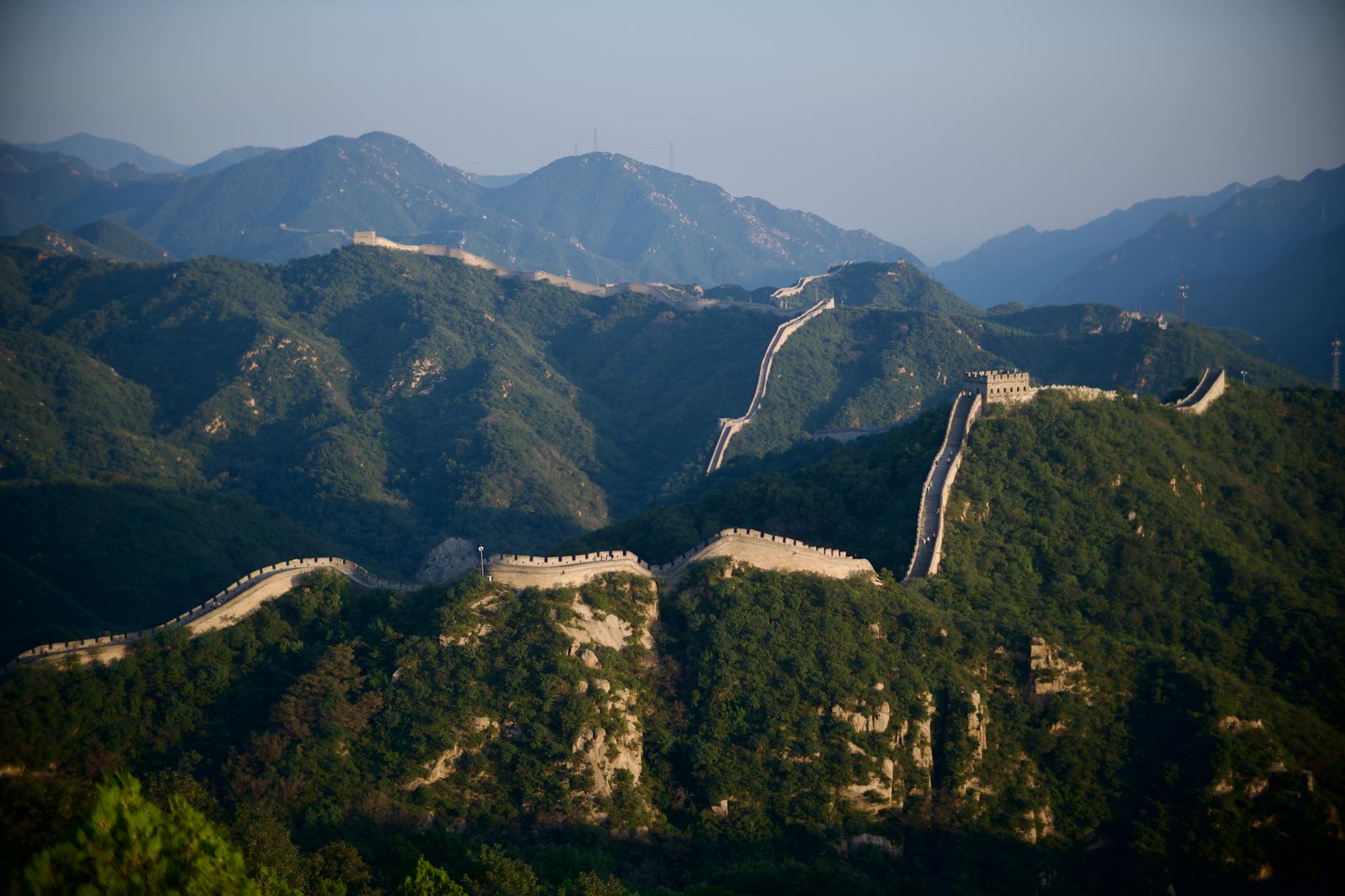 Scenic view of the Great Wall of China stretching over lush mountains.
