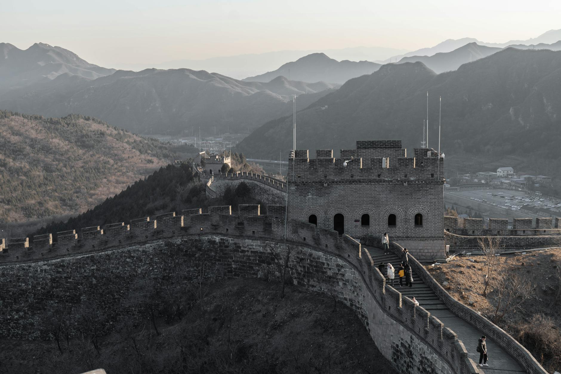 Majestic view of the Great Wall of China winding through mountains at sunset with few visitors.