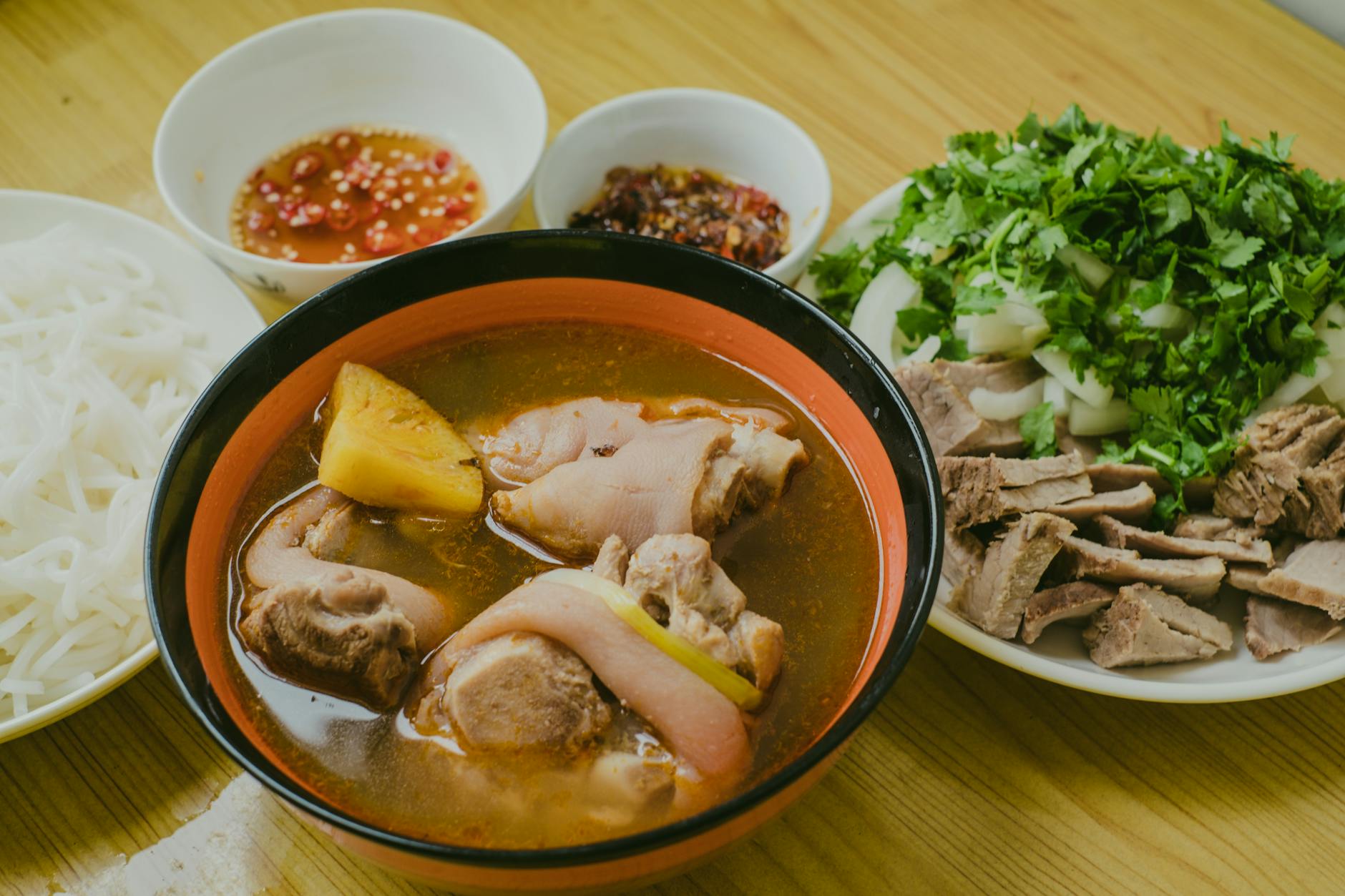 Close-up of Vietnamese pho served with herbs and spices, showcasing a traditional meal arrangement.