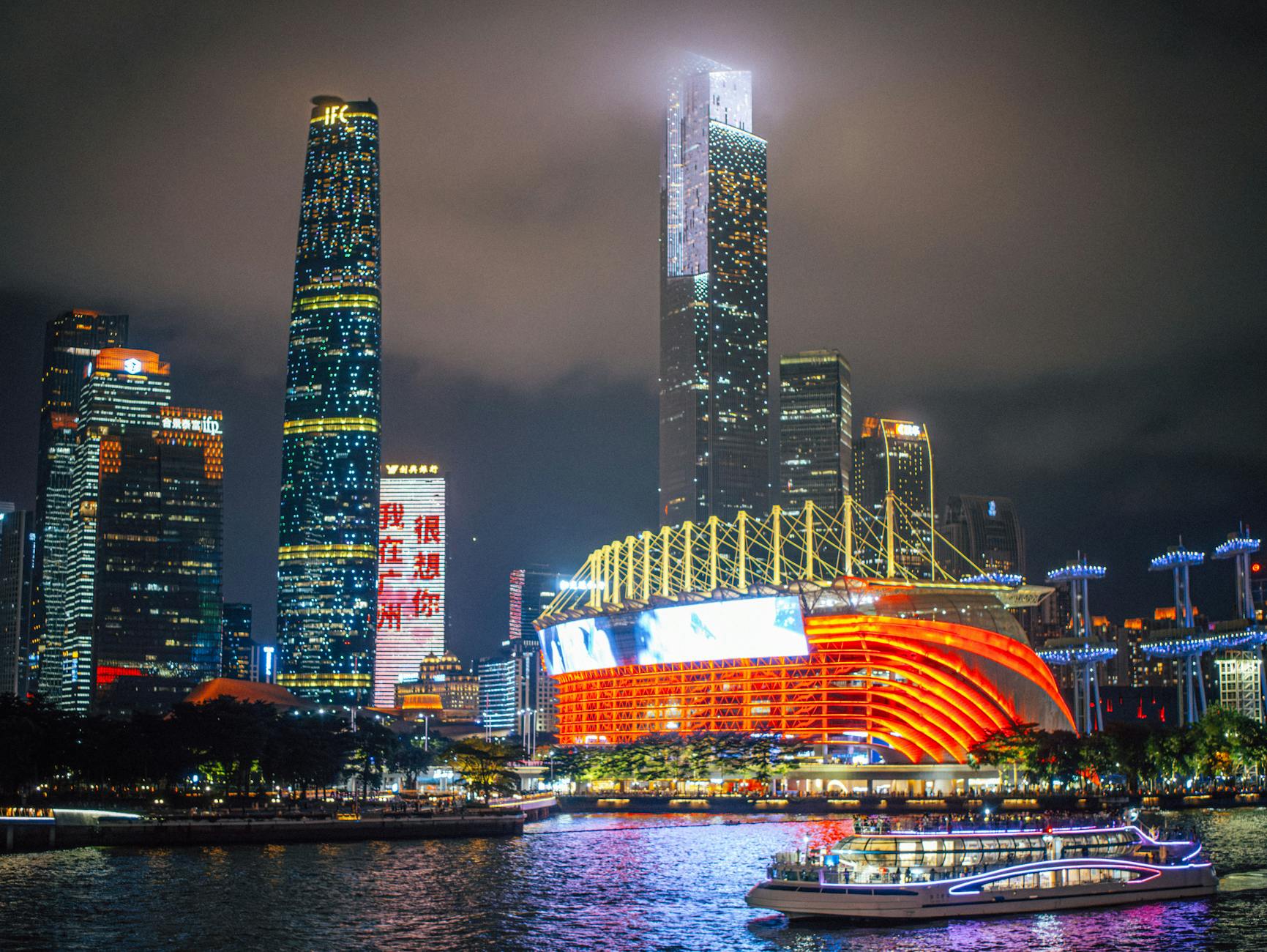 Stunning nighttime view of Guangzhou skyline with illuminated skyscrapers and riverfront.