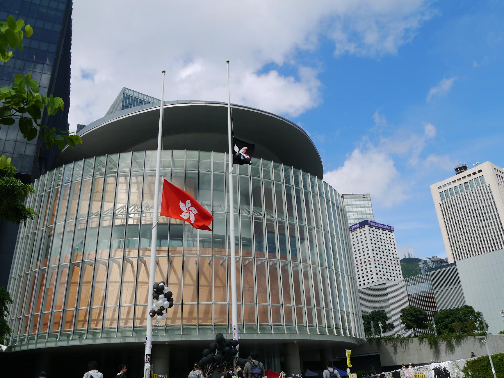Contemporary Hong Kong architecture featuring flags, glass windows, and urban skyline.