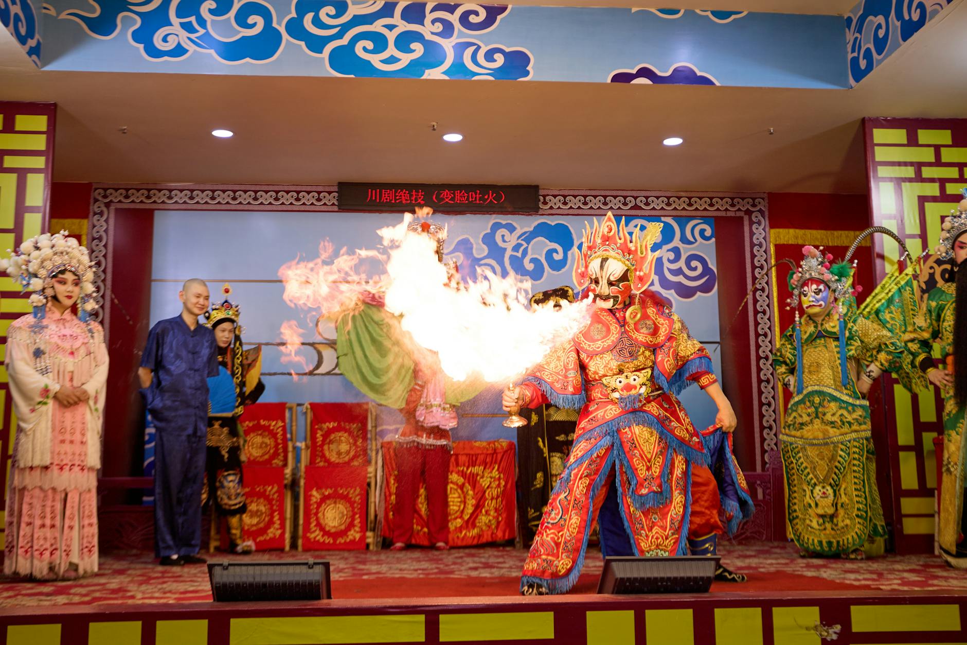 Vibrant Chinese opera scene featuring dramatic fire-breathing act on stage.