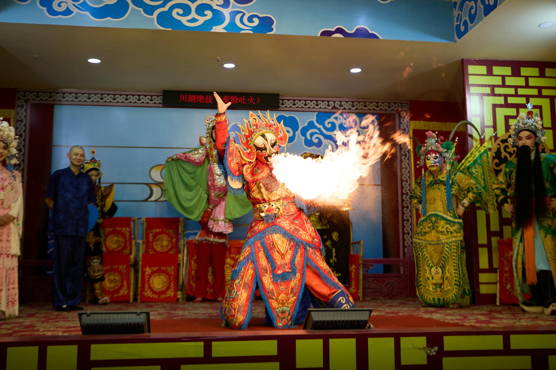 Colorful Chinese opera performance featuring a fire-breathing act on stage.