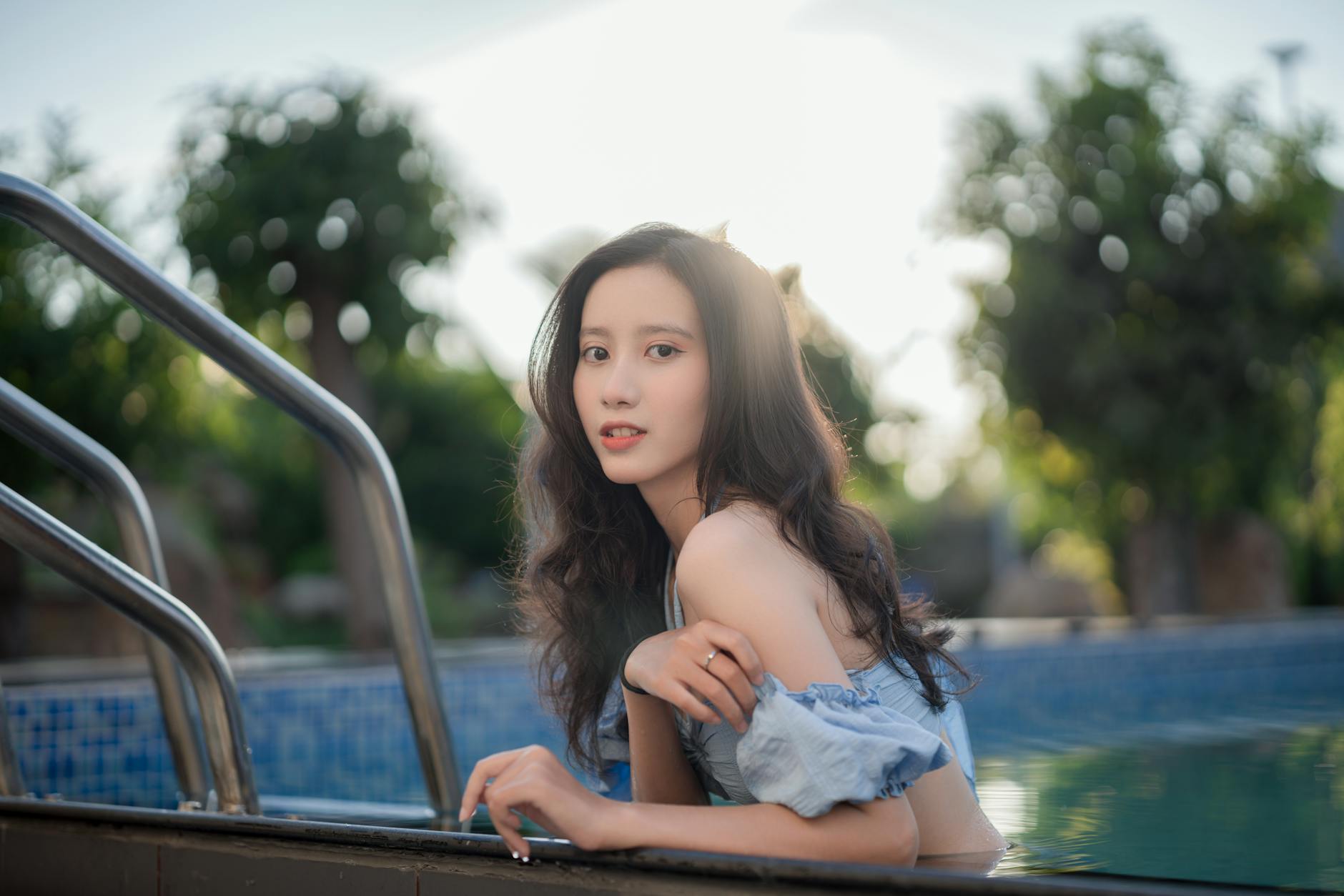 Beautiful young woman enjoying a sunny day in a swimming pool outdoors.