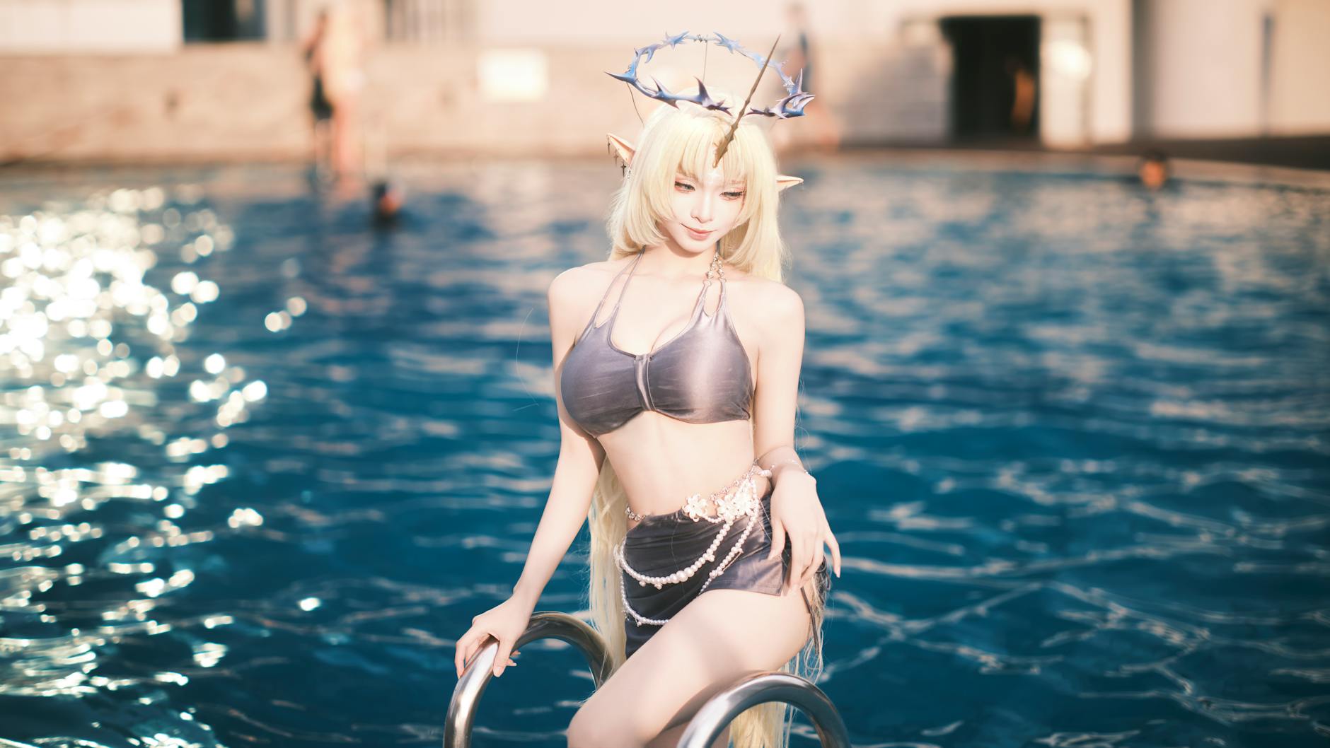Cosplayer posing as a fantasy character with antlers by a swimming pool.
