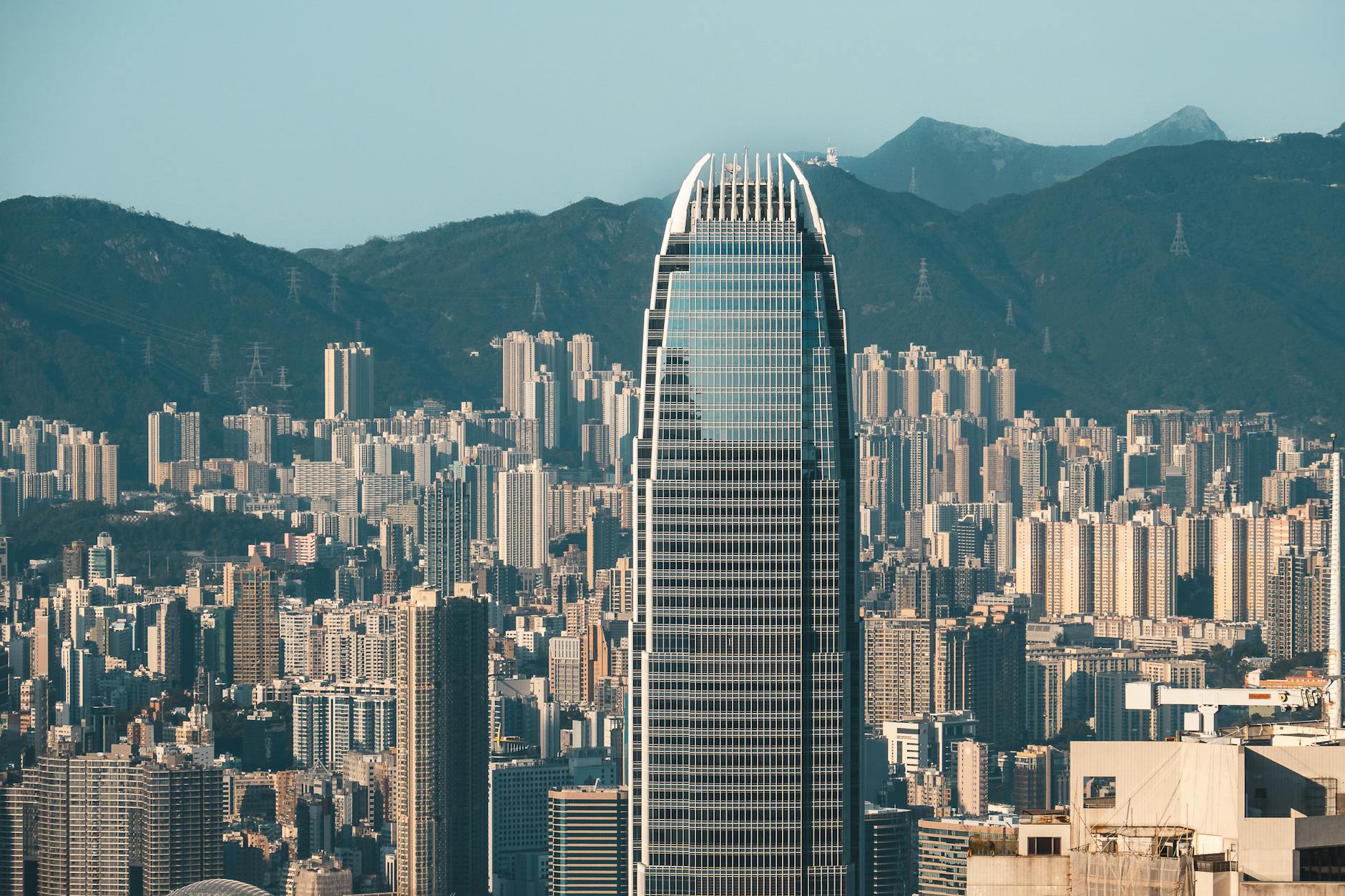 A striking view of Hong Kong's skyline with a prominent skyscraper against mountain backdrop.