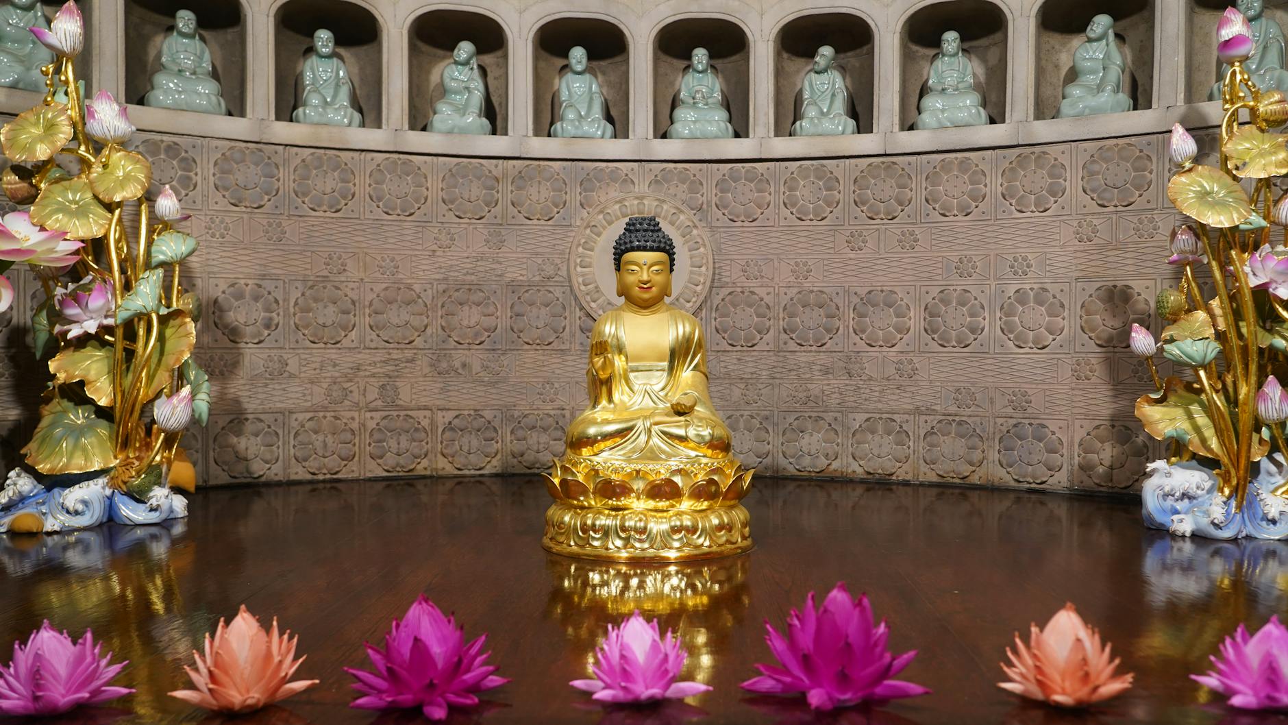 A serene golden Buddha statue surrounded by vibrant lotus flowers inside a Seoul temple.