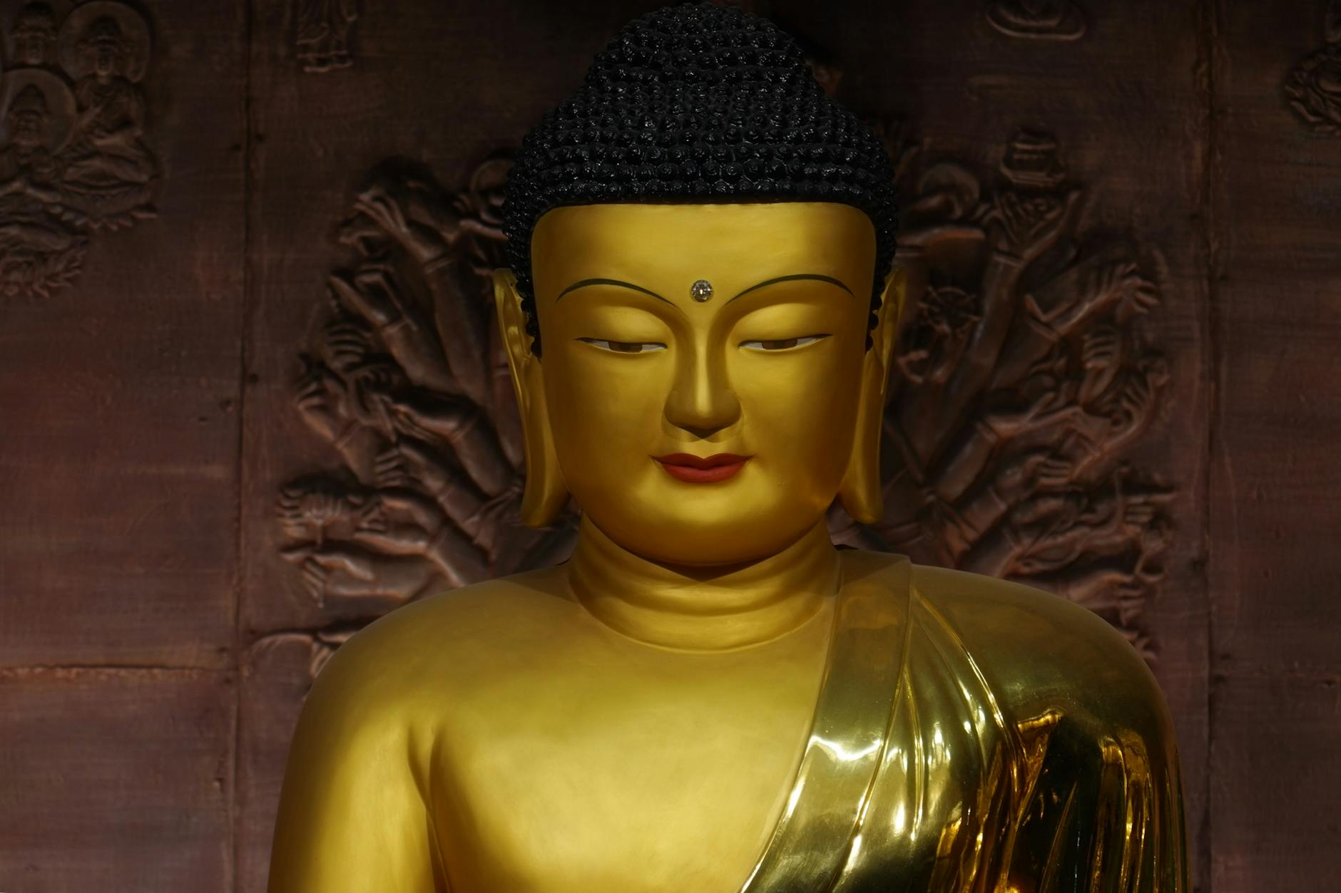 Serene golden Buddha statue against detailed carved backdrop in a Seoul temple.