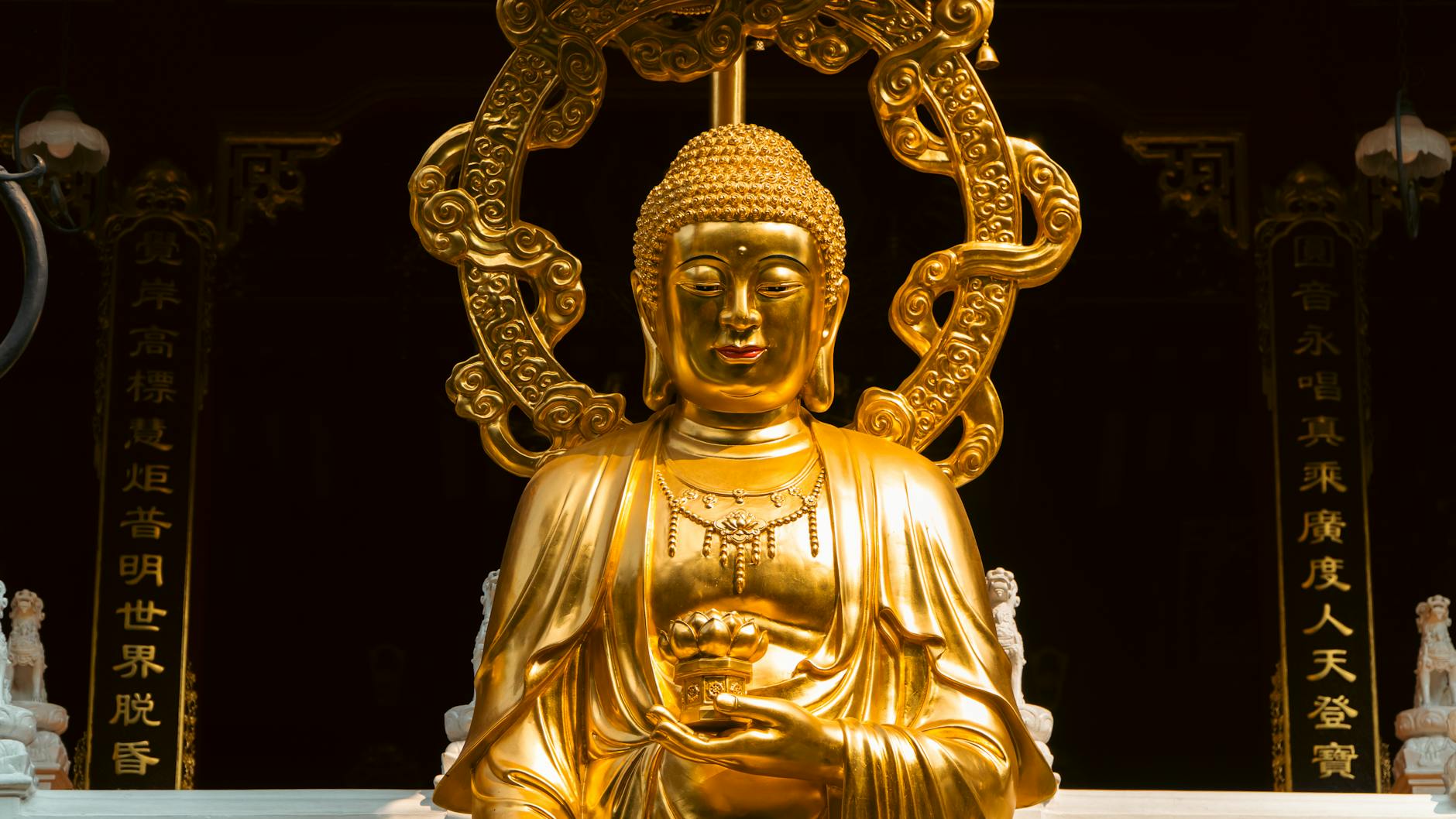 Close-up of a golden Buddha statue in an ornate Asian temple.