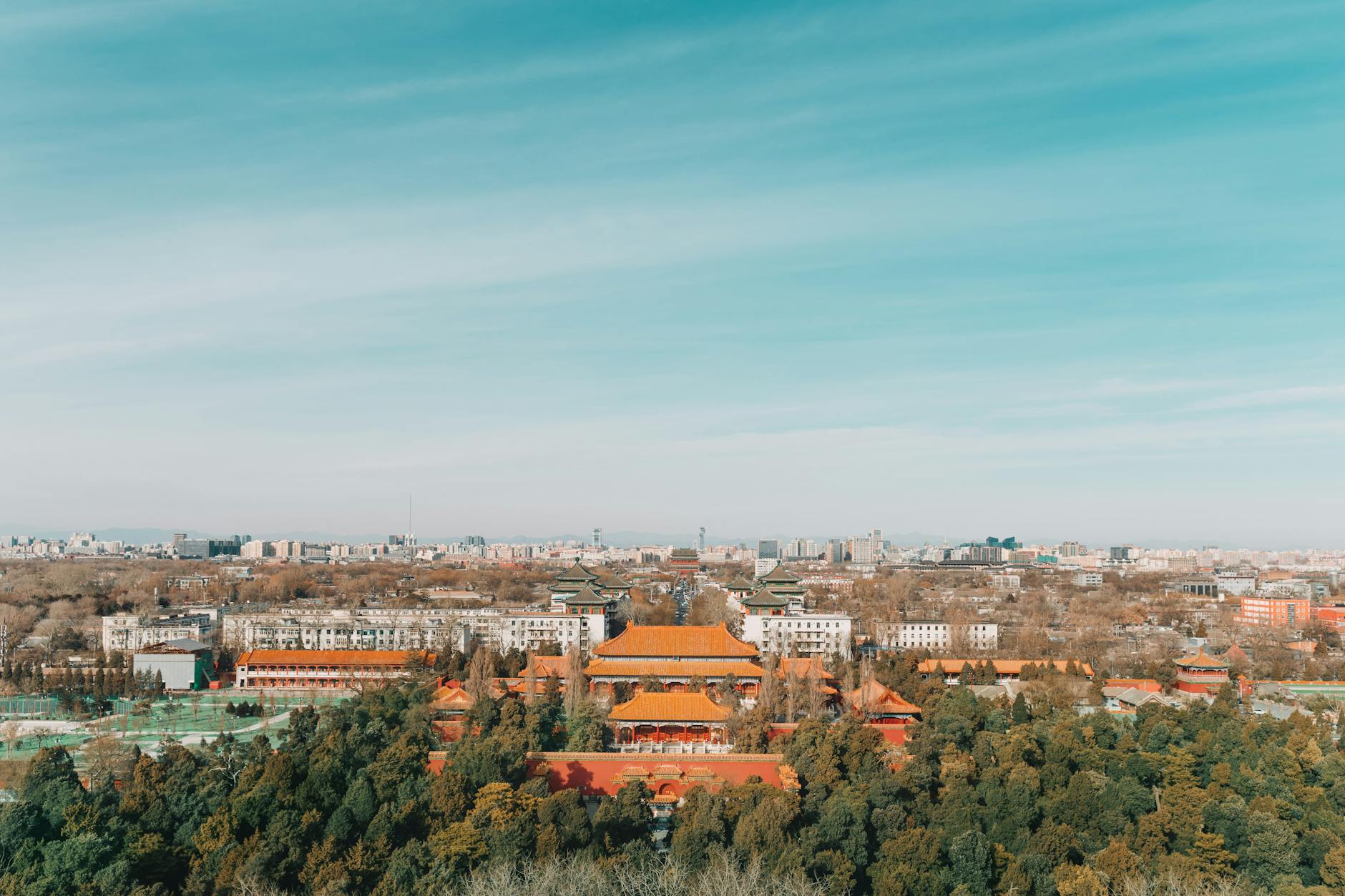 Stunning aerial view of Beijing's Forbidden City amidst urban skyline, capturing historic architecture and modern buildings.