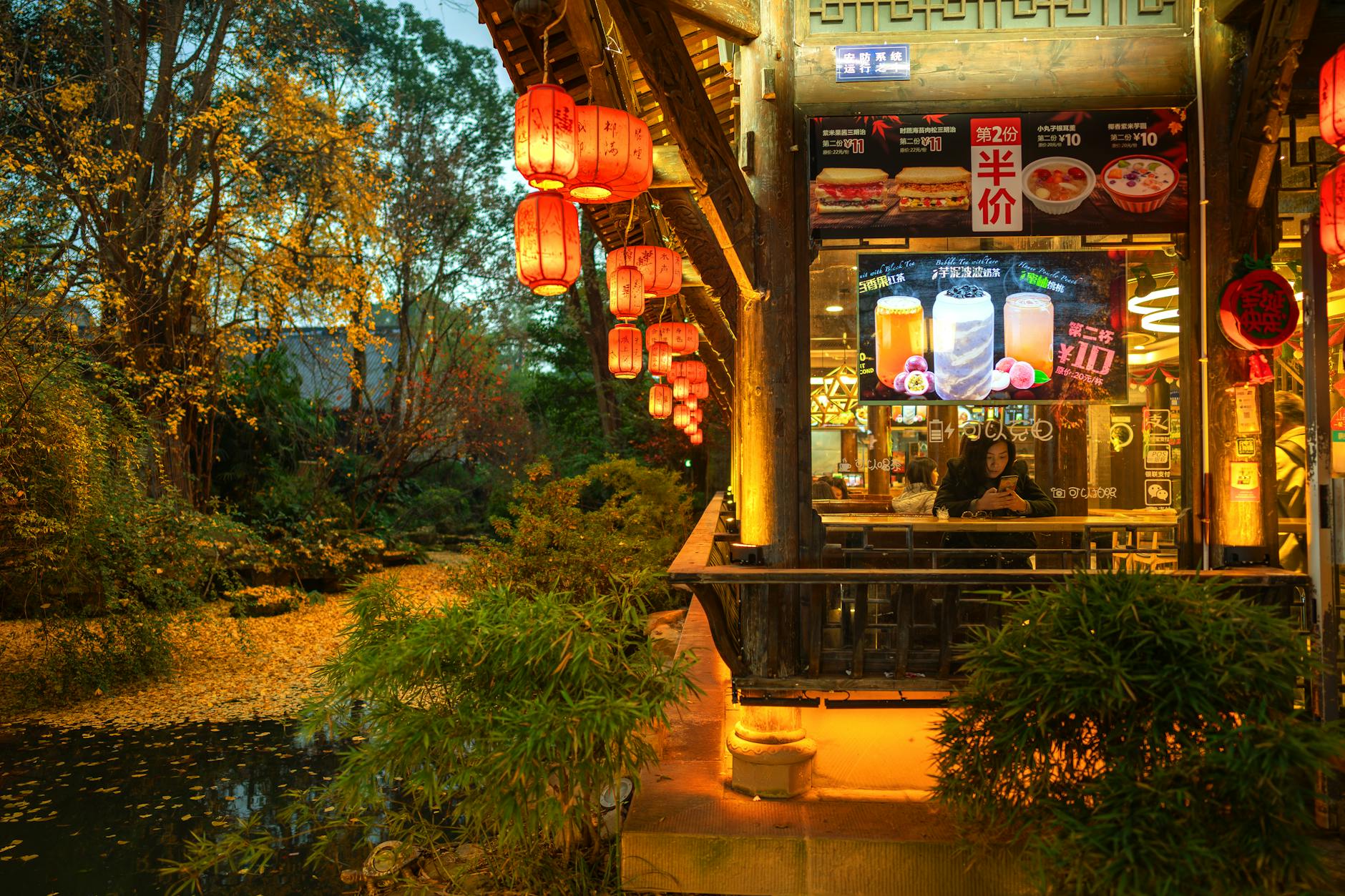 A cozy Chinese restaurant by the river with red lanterns glowing warmly at night in Chengdu, China.