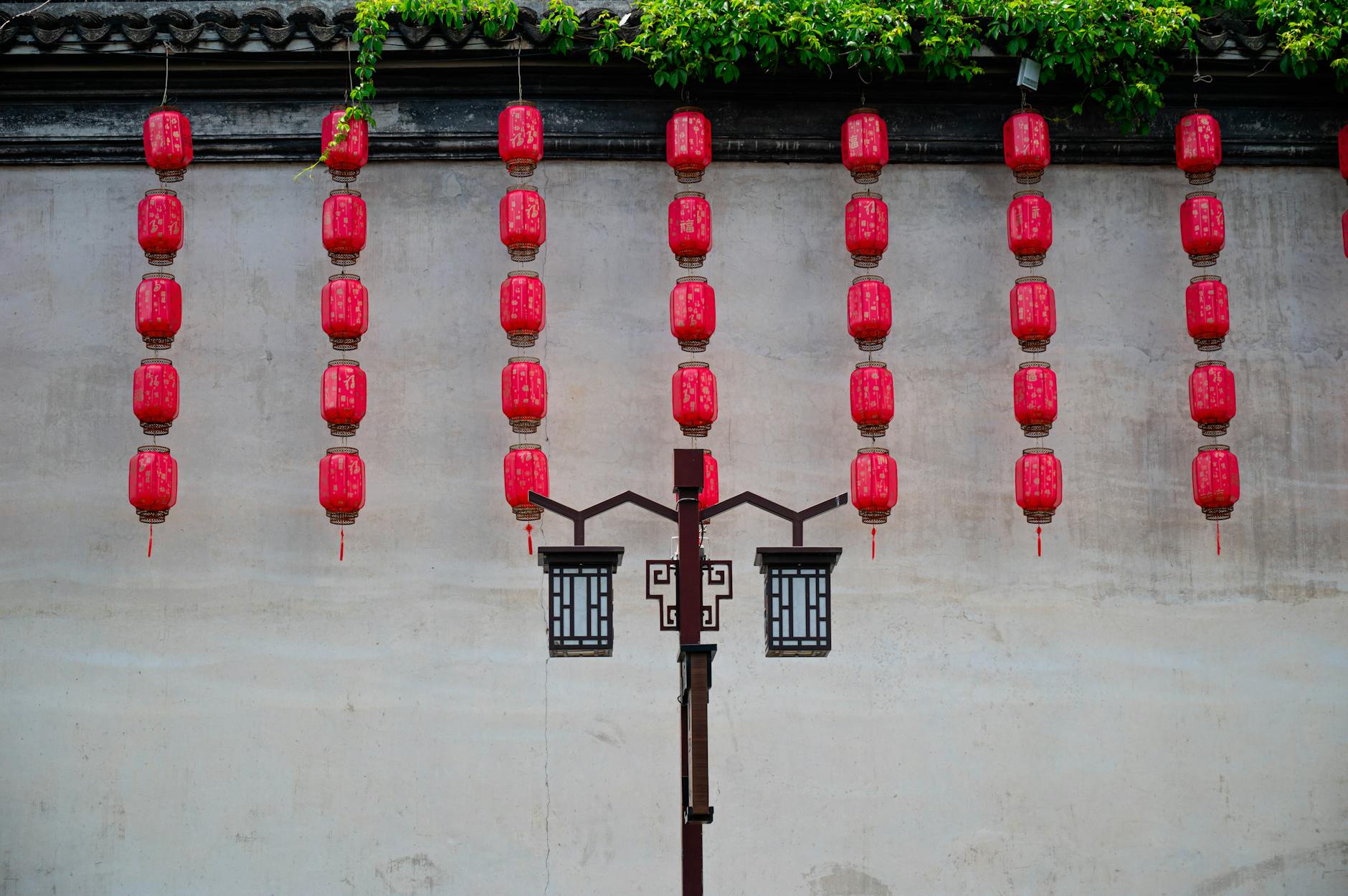 Rows of red lanterns hang on a traditional wall, evoking cultural elegance and design.