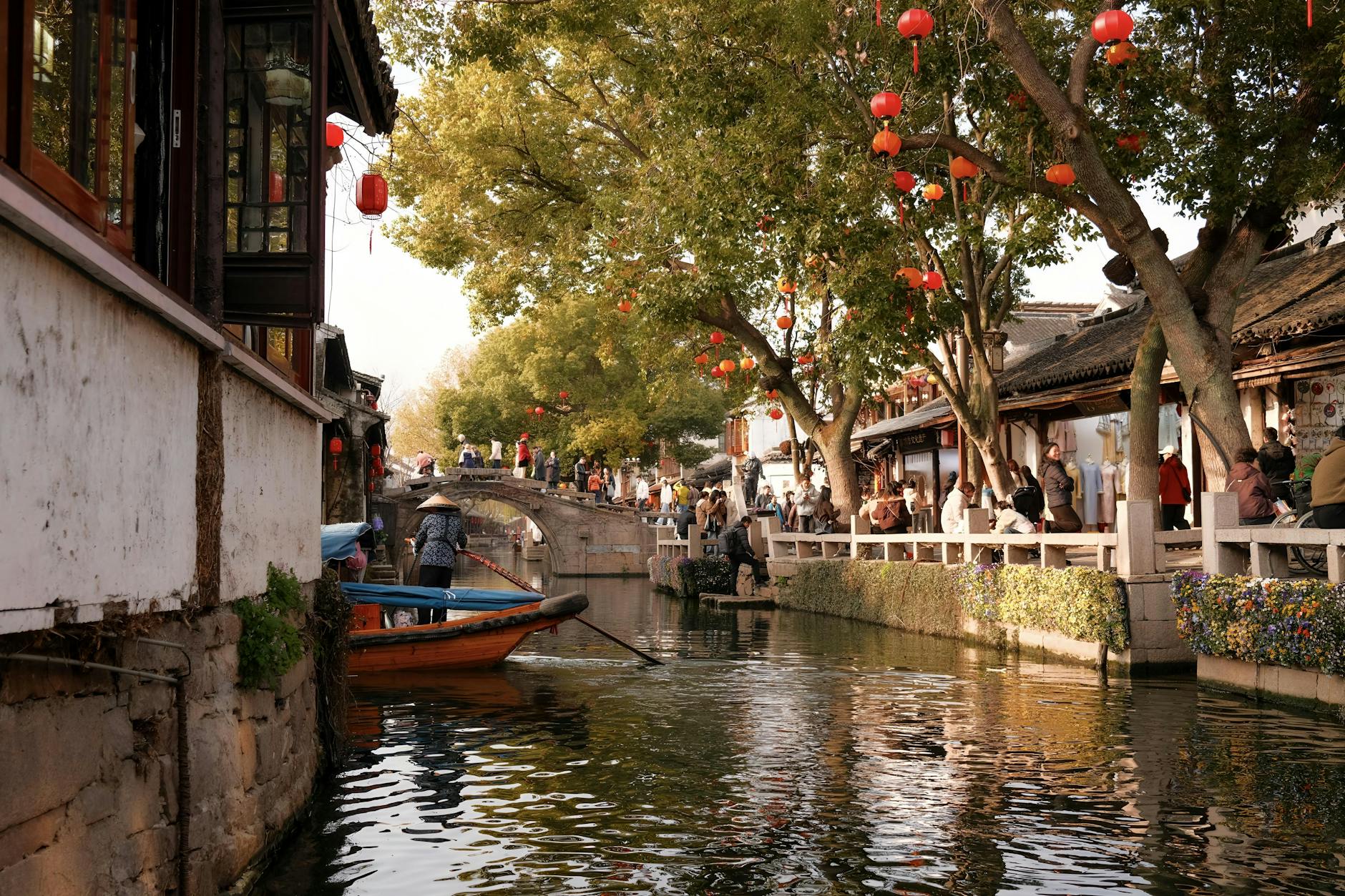 Picturesque canal in Suzhou, China with red lanterns and traditional architecture during the day.