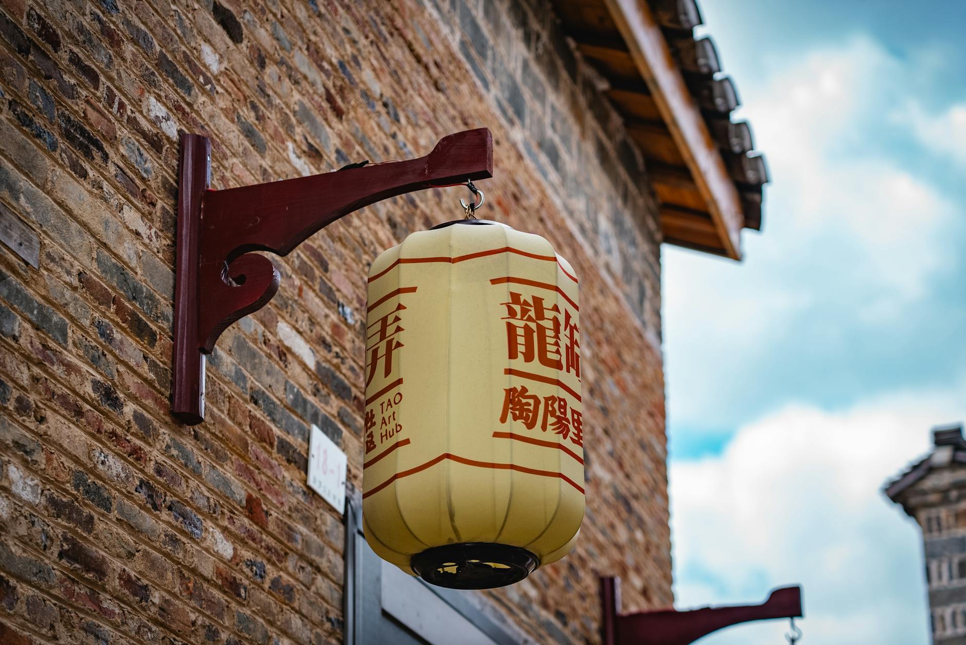 Close-up of a classic Chinese lantern hanging on a historic brick building, capturing cultural essence.