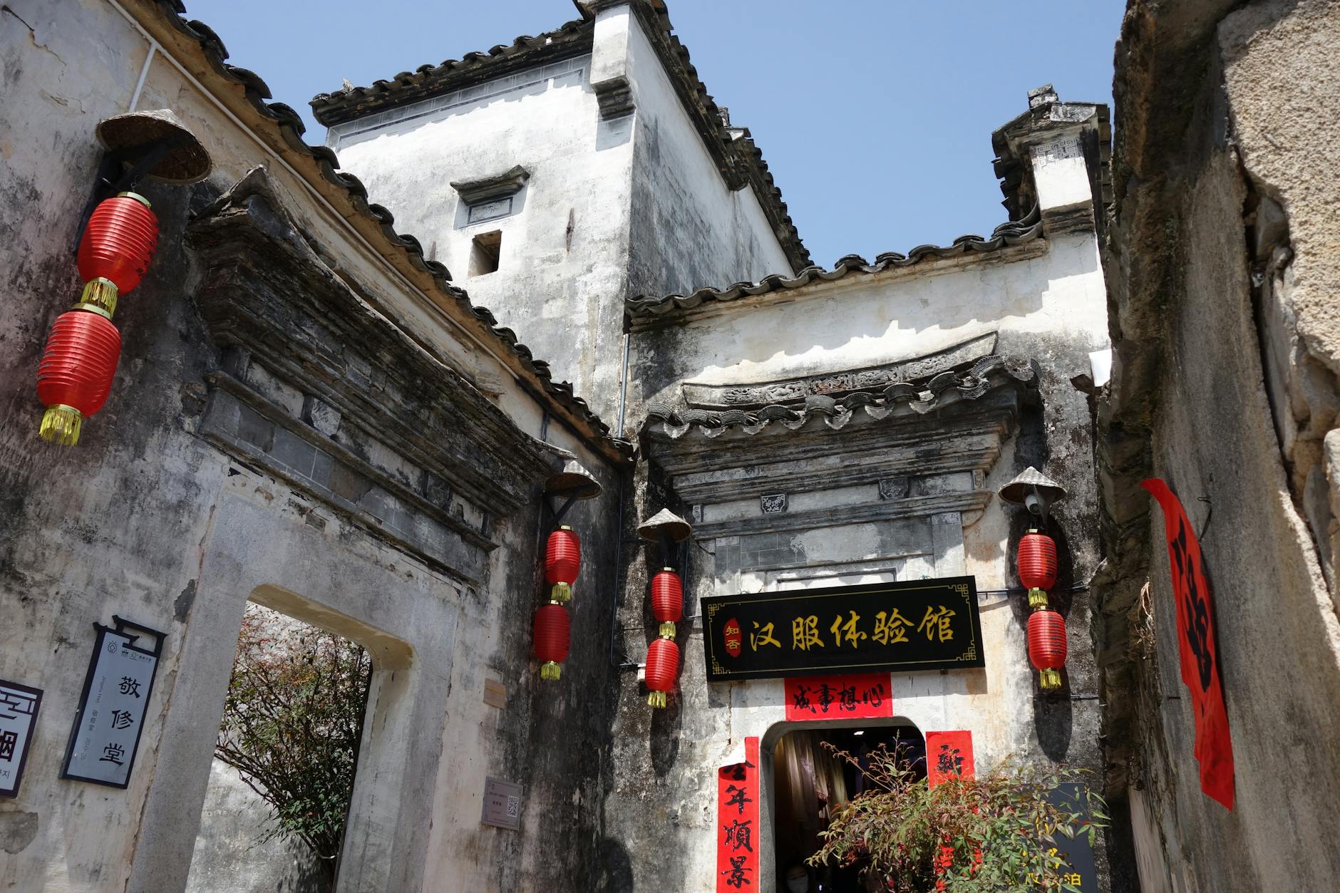 Ancient Chinese building adorned with red lanterns and decorative calligraphy signs, capturing cultural heritage.