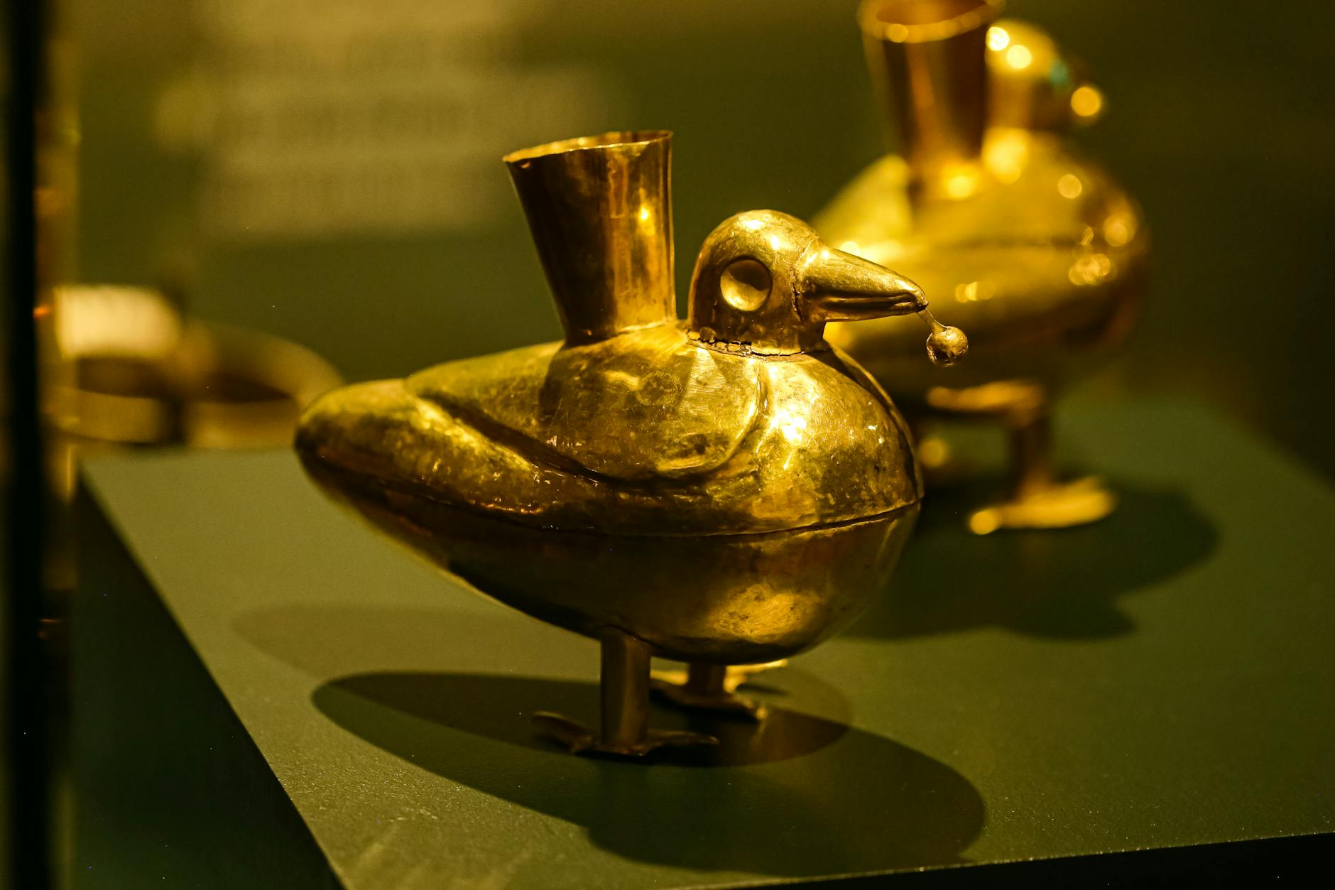Intricate golden bird-shaped artifacts displayed in a museum showcase, showcasing ancient craftsmanship.