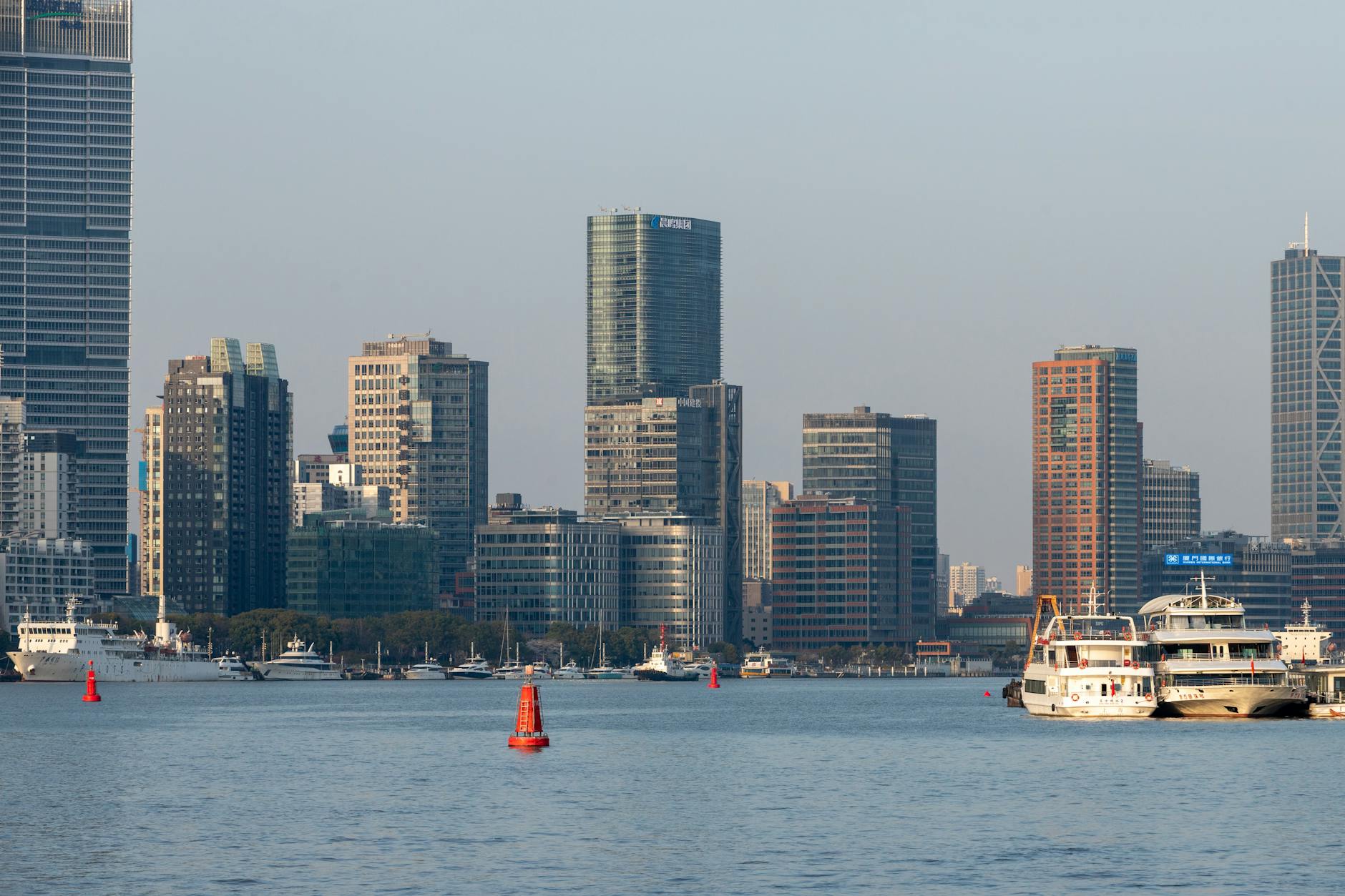 Modern skyline of Shanghai with waterfront boats on the Huangpu River.