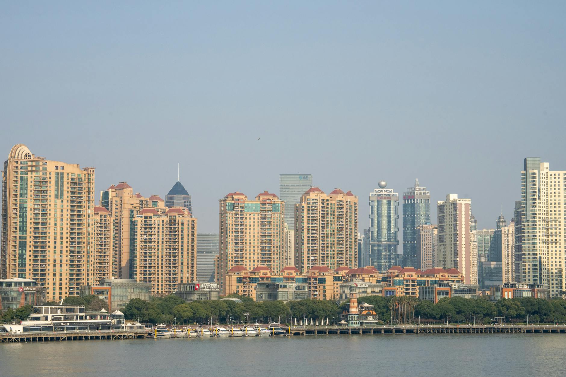 A beautiful daytime view of Shanghai's modern skyline with prominent skyscrapers and a waterfront setting.