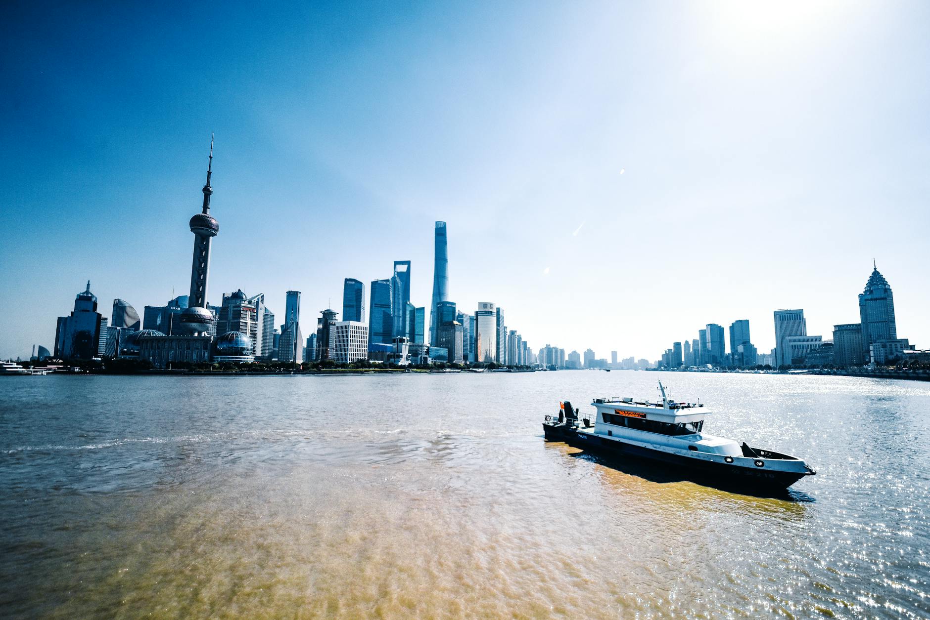 Scenic view of Shanghai's modern skyline and skyscrapers on a clear day with a boat on the Huangpu River.