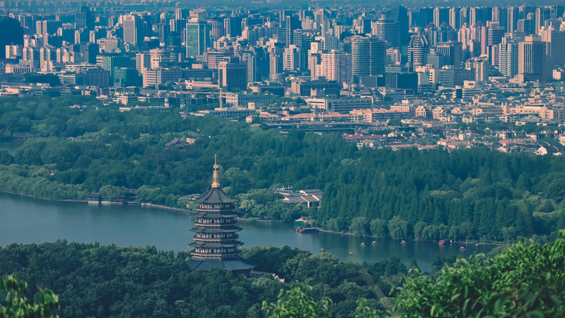 A breathtaking view of Leifeng Pagoda surrounded by lush greenery and urban skyline in Hangzhou, China.