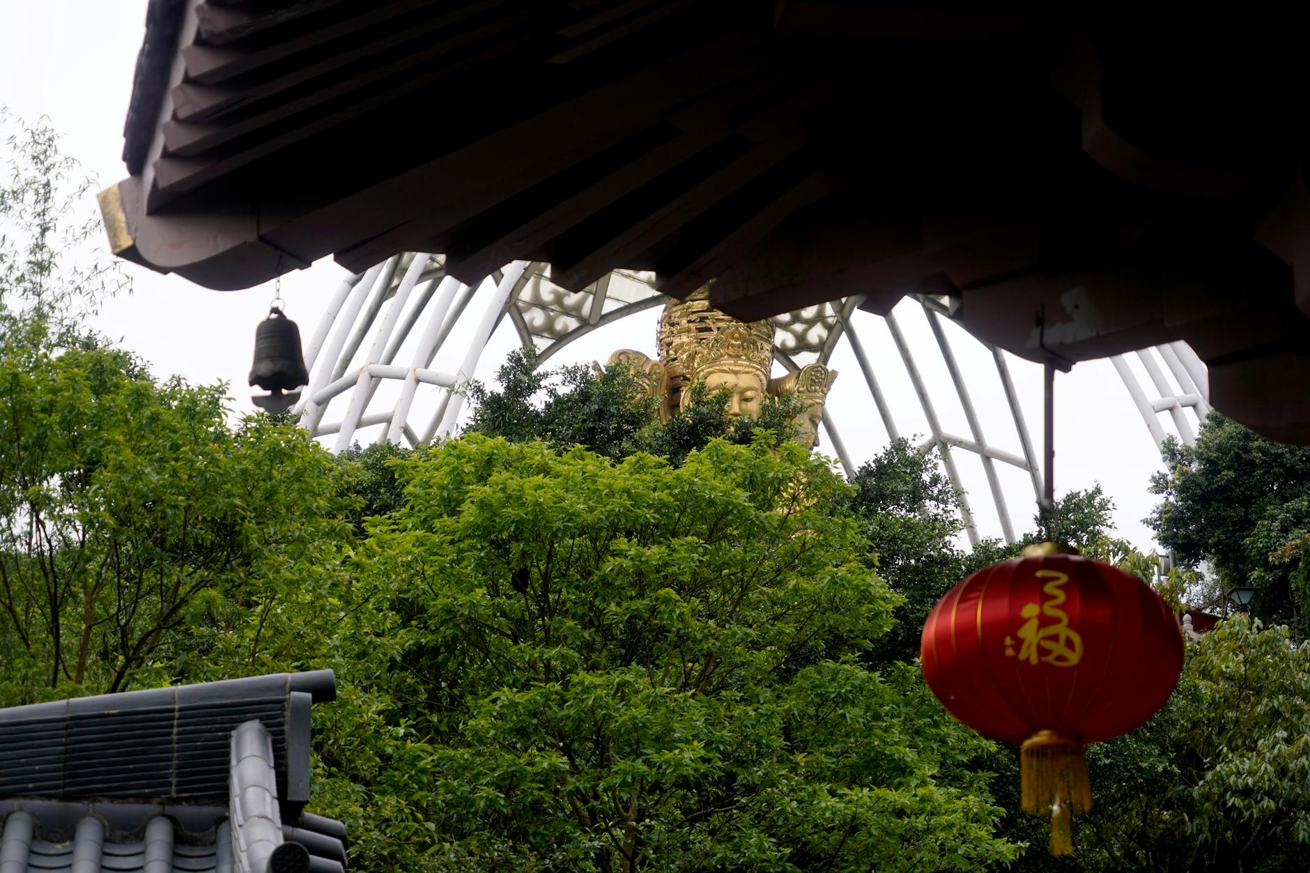 Serene view of a Buddhist temple with red lanterns amidst lush greenery, highlighting spirituality and traditional architecture.