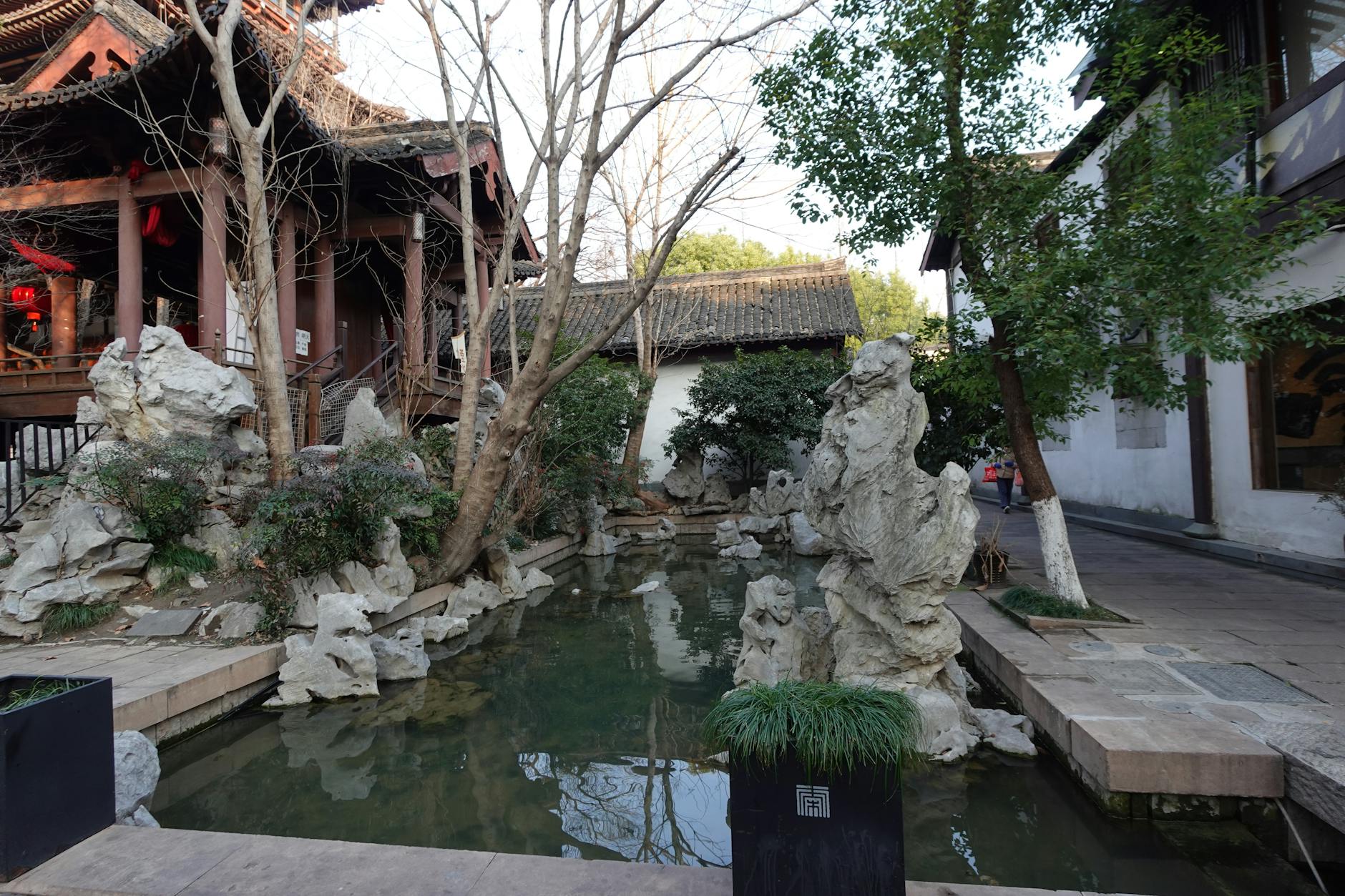 A serene Chinese garden with traditional architecture and natural rock formations in Hangzhou.
