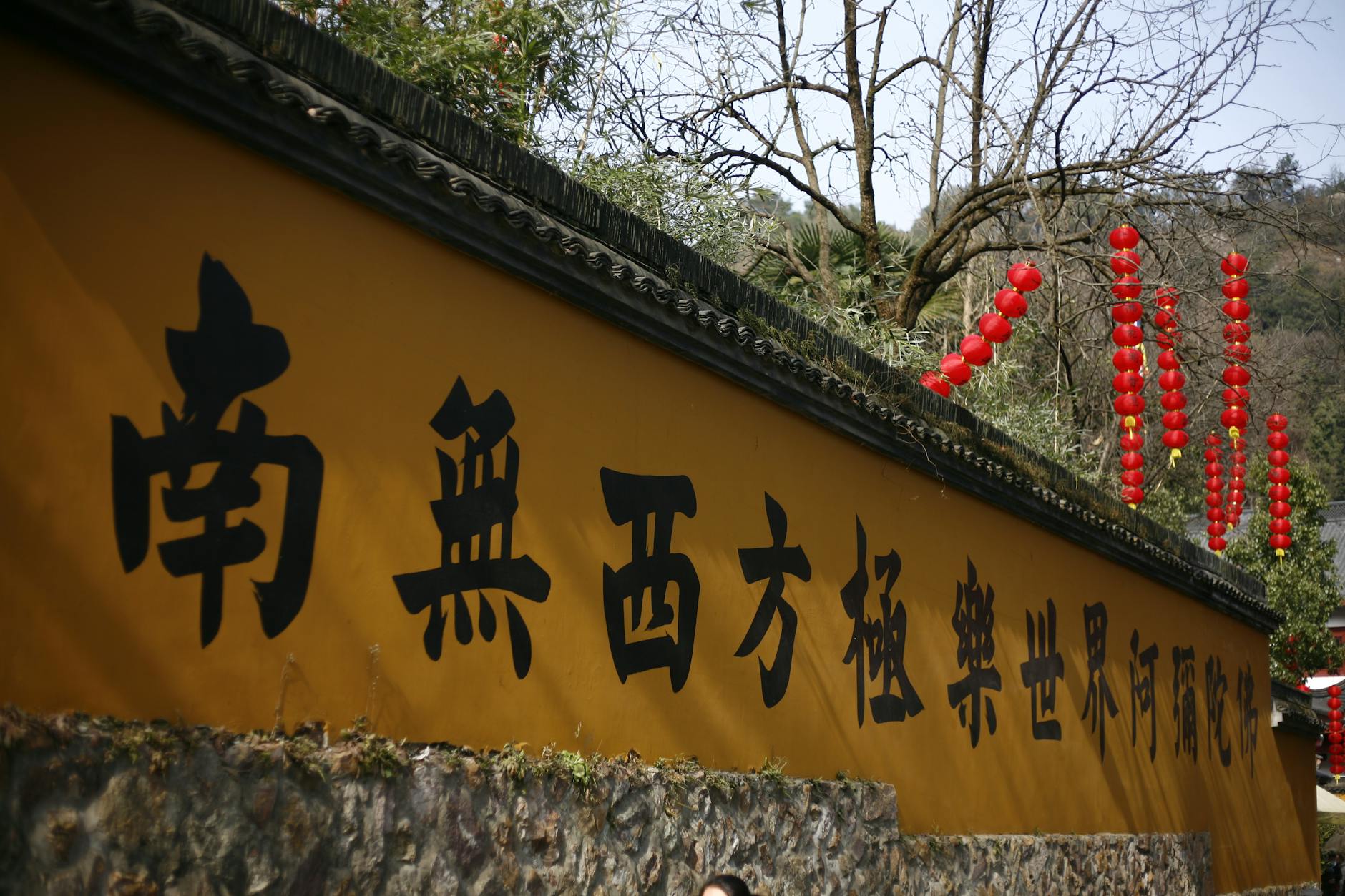 Vibrant yellow wall with lanterns and Chinese script at a temple in Hangzhou, China.