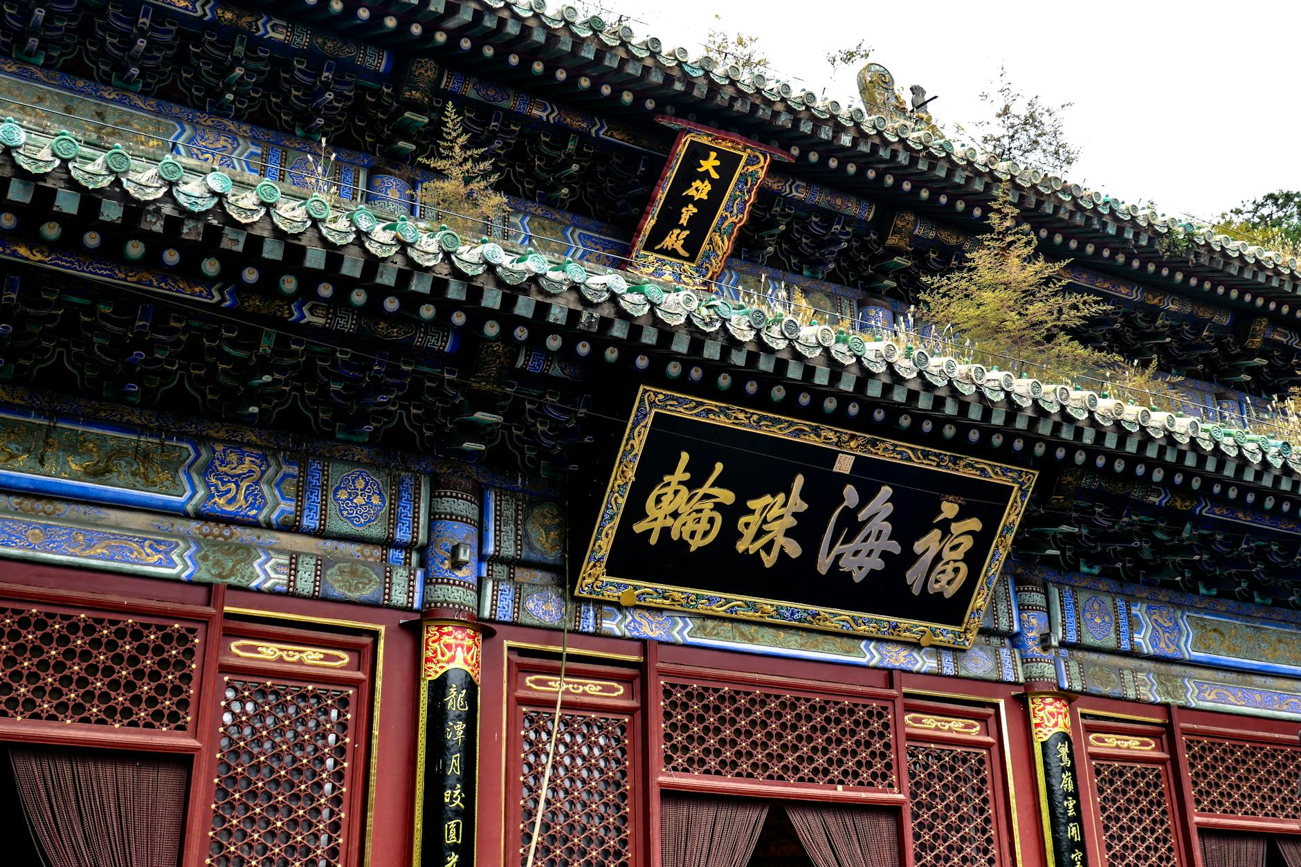 Detailed view of a colorful ornate temple roof in traditional Chinese architecture with intricate carvings and calligraphy.
