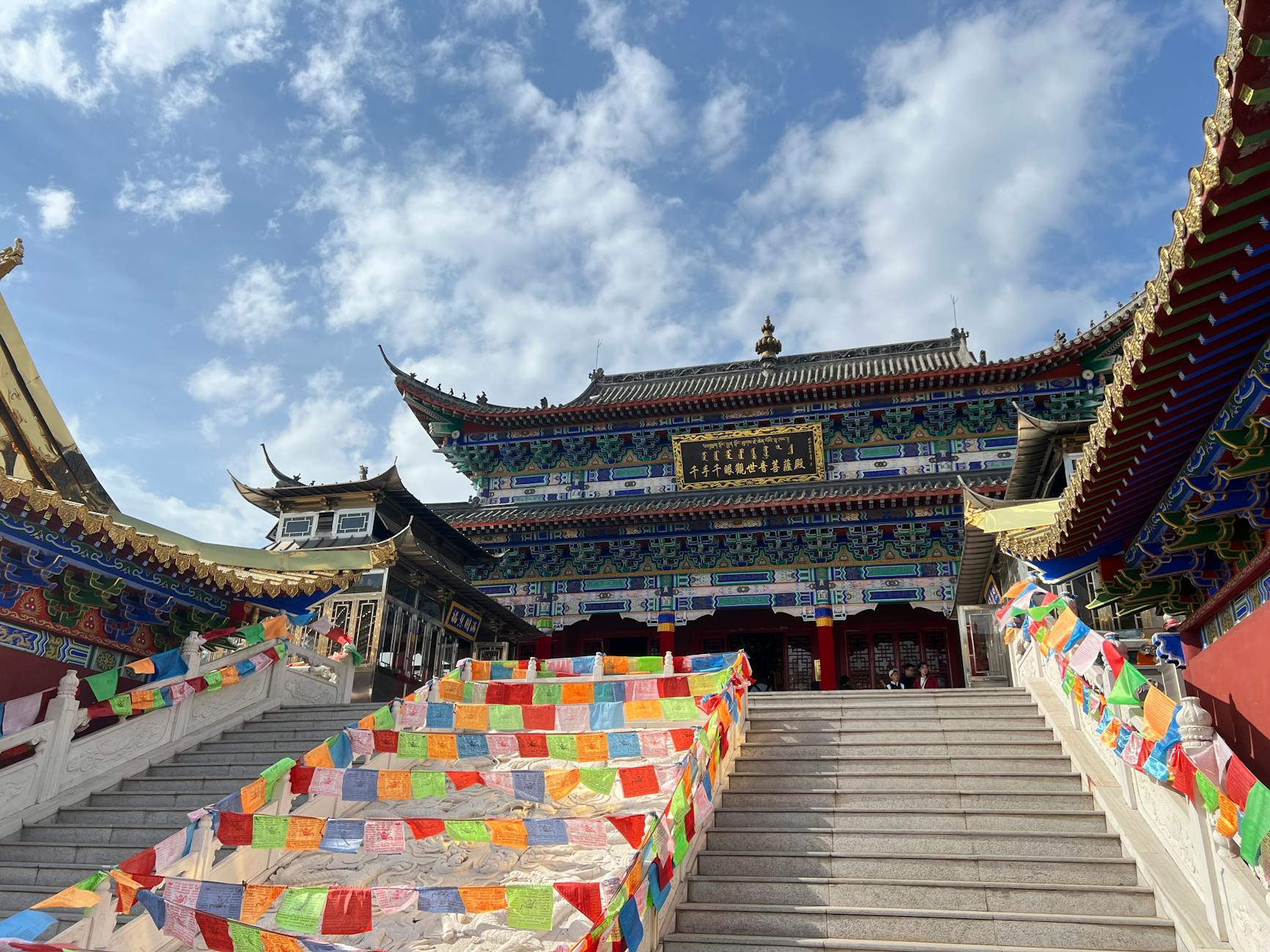 A vibrant Tibetan temple adorned with colorful prayer flags under a bright blue sky.
