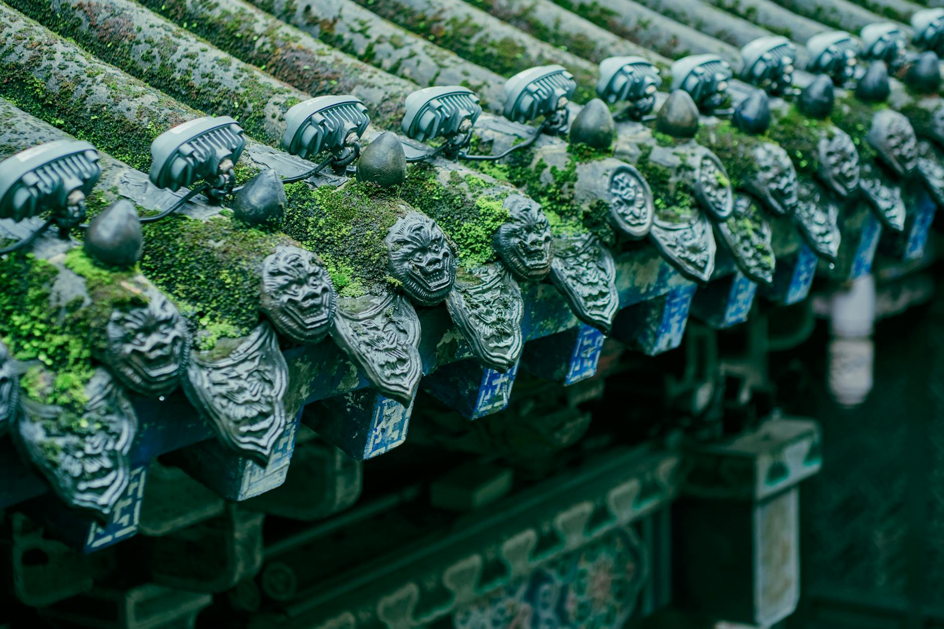 Close-up of ornate, moss-covered decorative roof elements on a traditional Chinese temple.