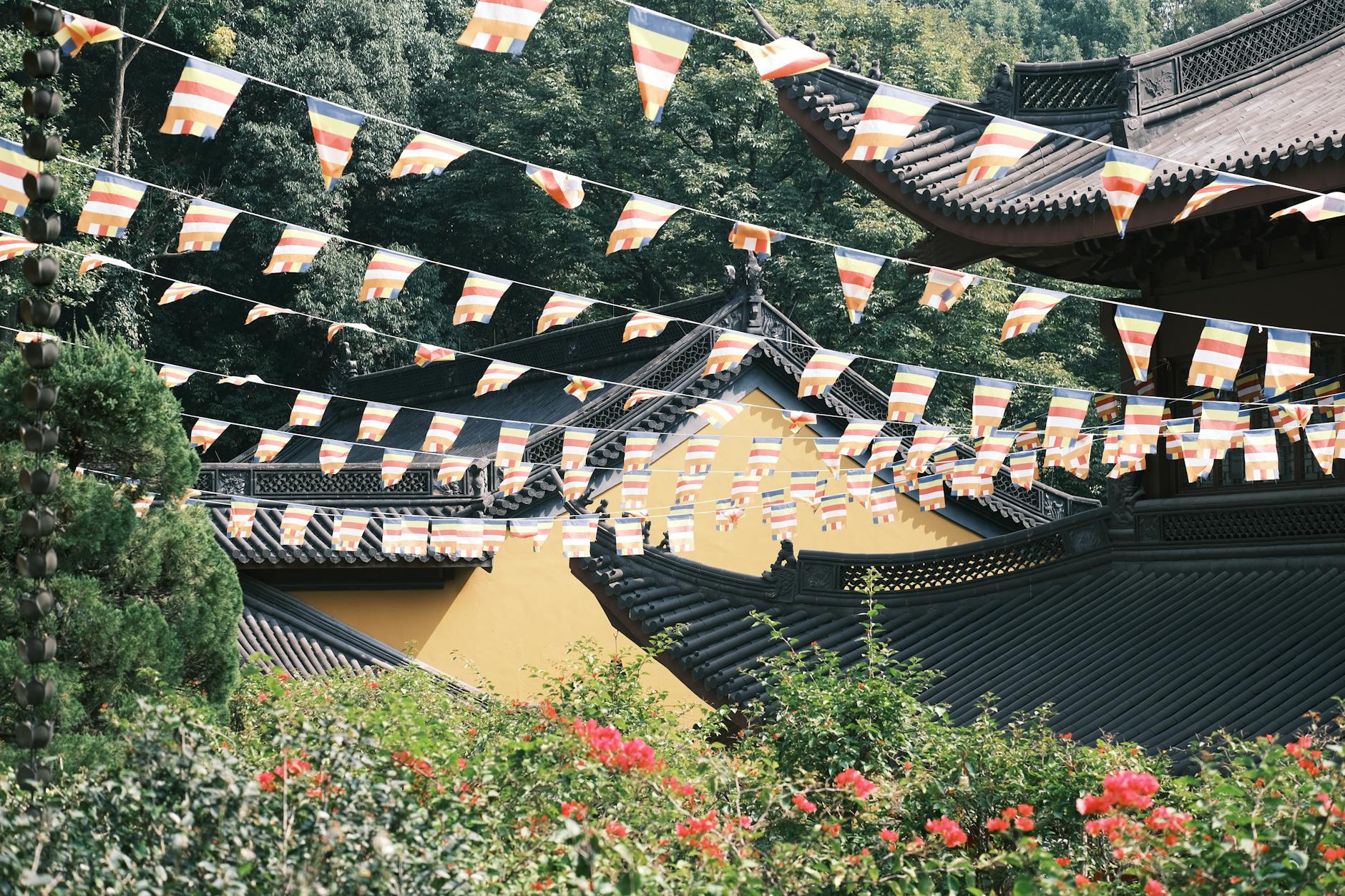 Beautiful view of traditional Asian roofs with colorful flags and lush greenery.