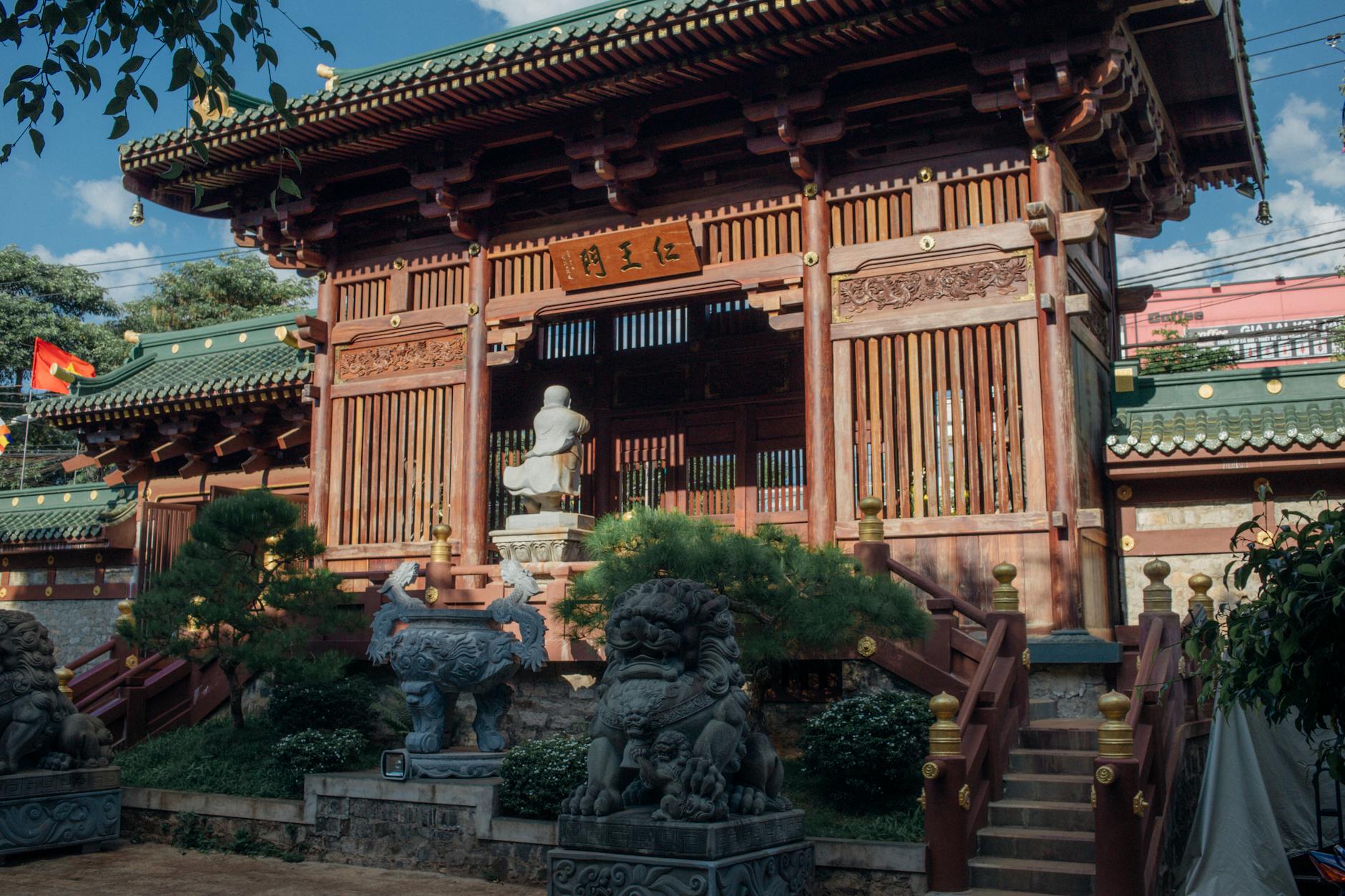 Exterior view of a traditional Vietnamese temple with intricate wooden architecture and stone sculptures.