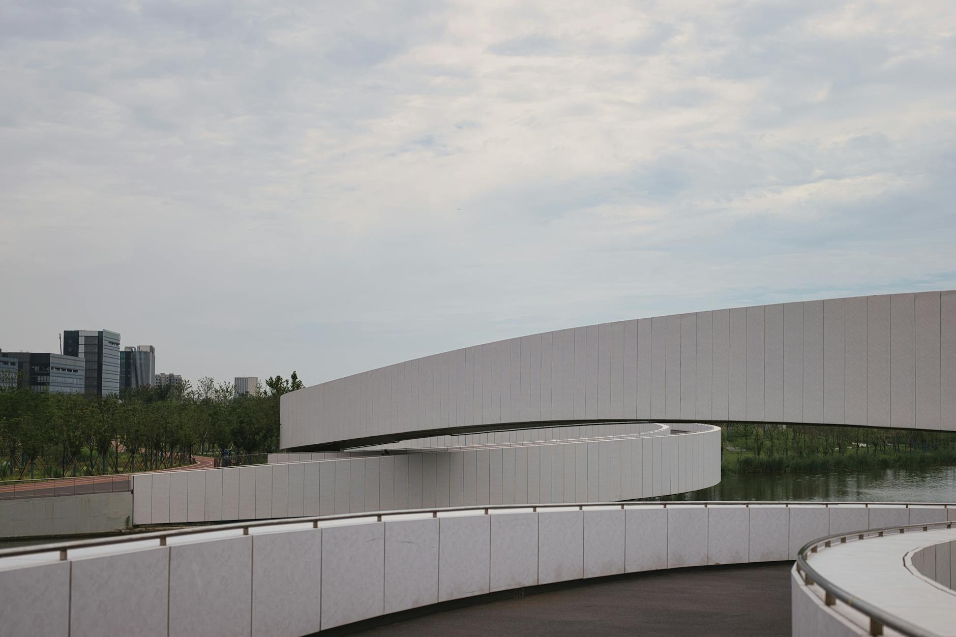 Curved modern bridge in Nanhuixincheng Town, Shanghai against cityscape.