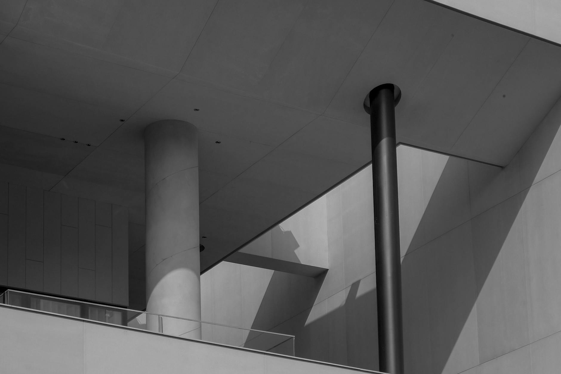 Abstract view of a modern architectural design featuring concrete pillars and dramatic shadows.