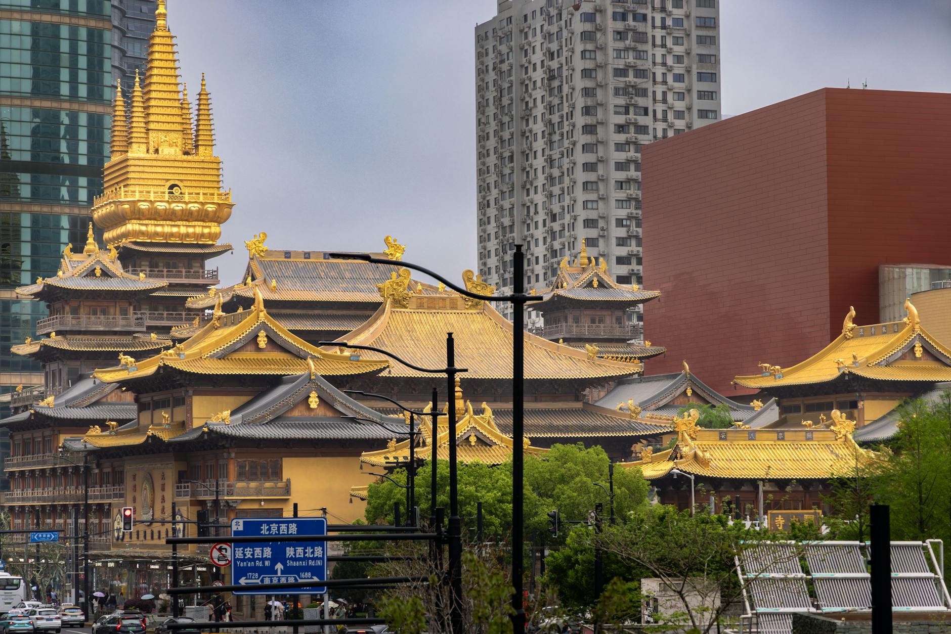 Jing'an Temple's golden rooftops surrounded by modern skyscrapers in Shanghai cityscape.