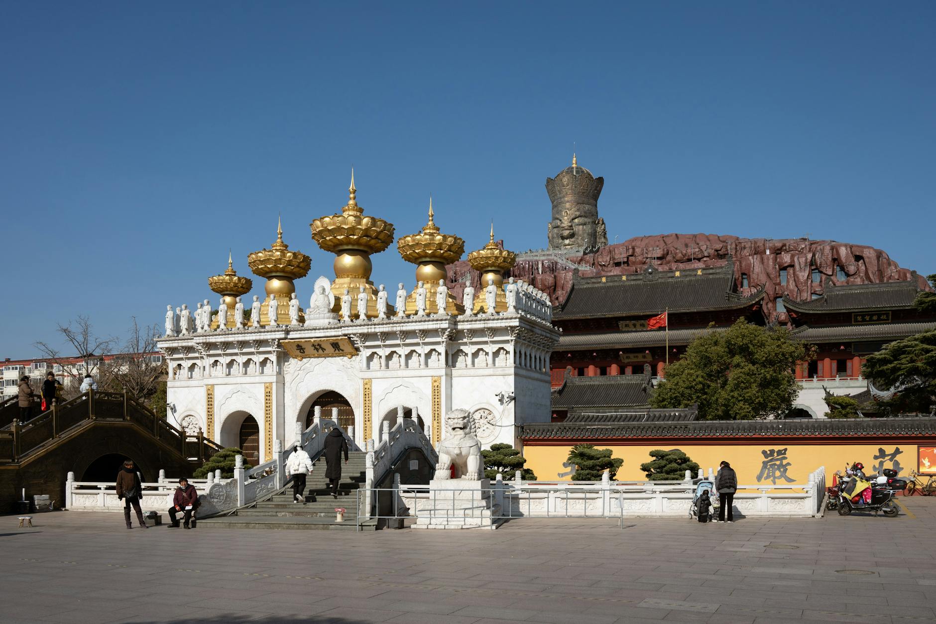 Explore the majestic Buddhist temple under a clear blue sky in Shanghai, capturing intricate gold details and ancient architecture.
