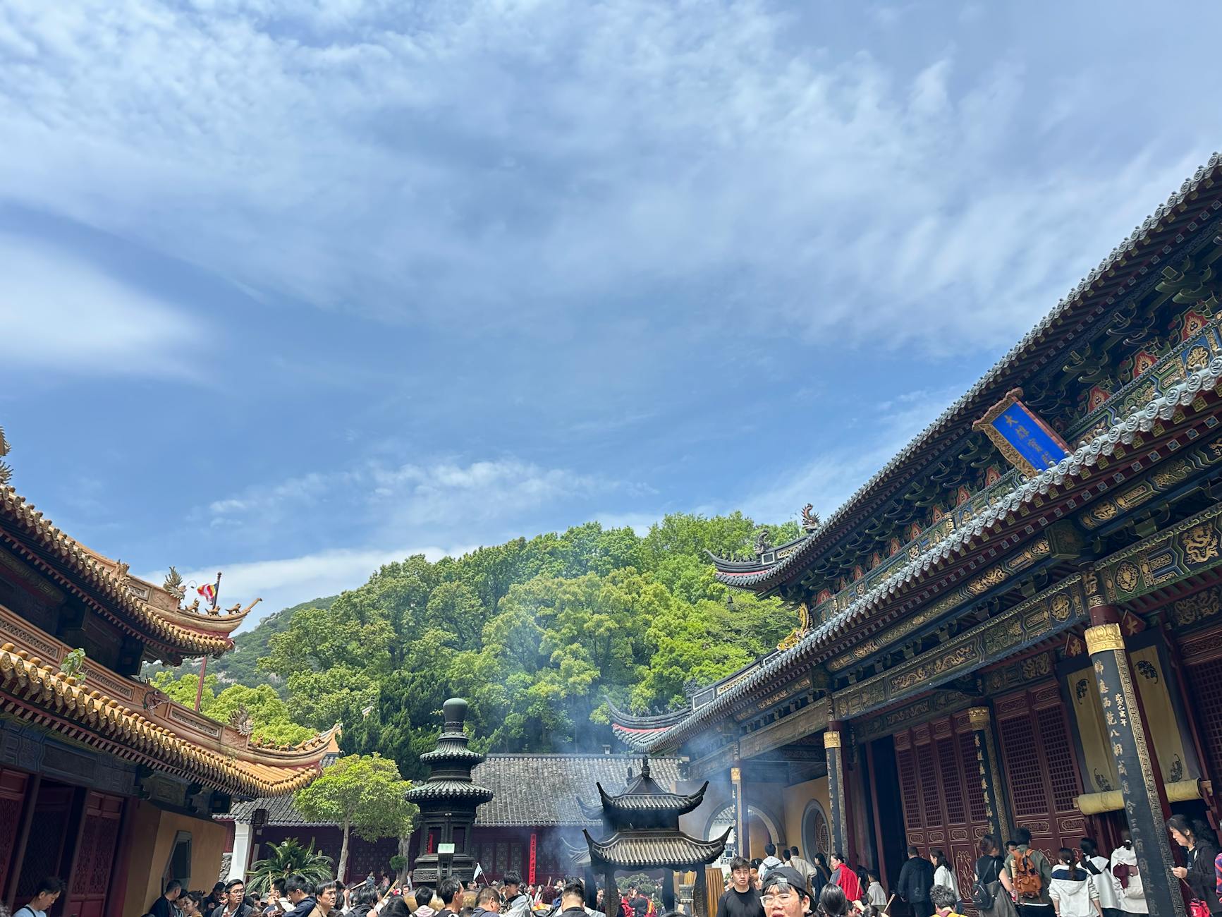 A bustling scene at a traditional Chinese temple with worshippers and architectural beauty under a clear blue sky.