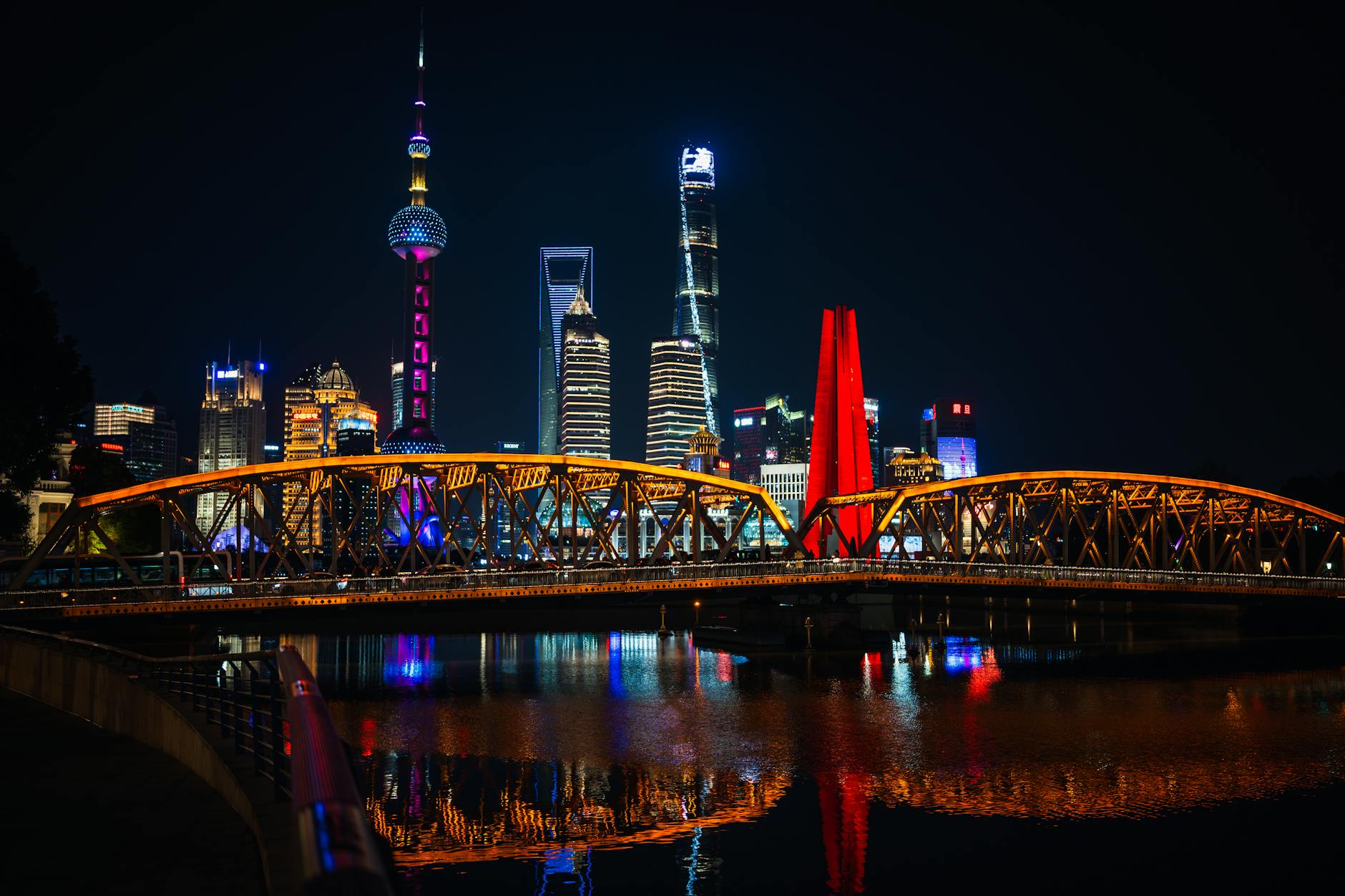 Captivating night cityscape of illuminated Shanghai skyline with iconic bridge reflection.