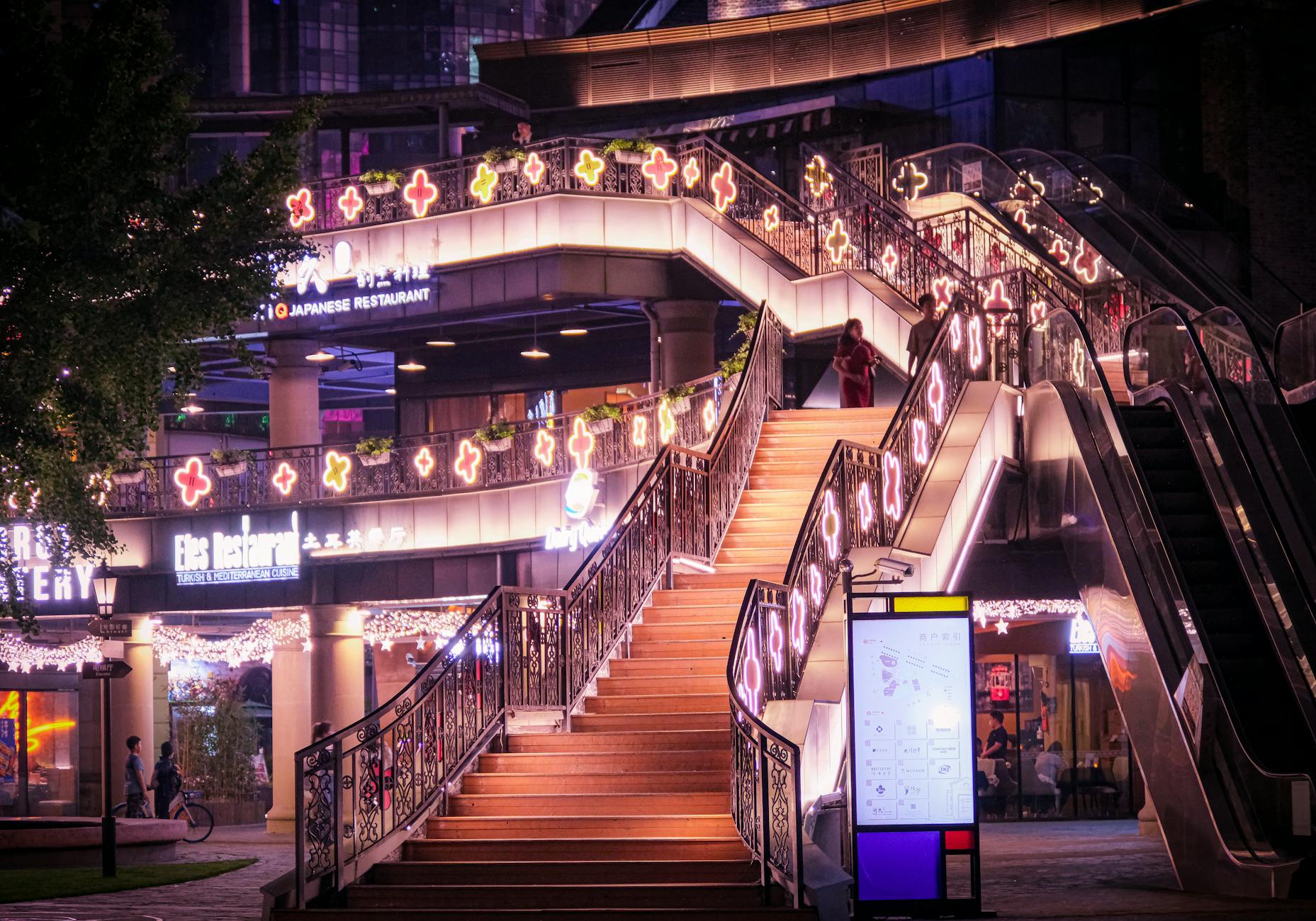 Colorful illuminated staircase in a lively Shanghai outdoor setting at night.