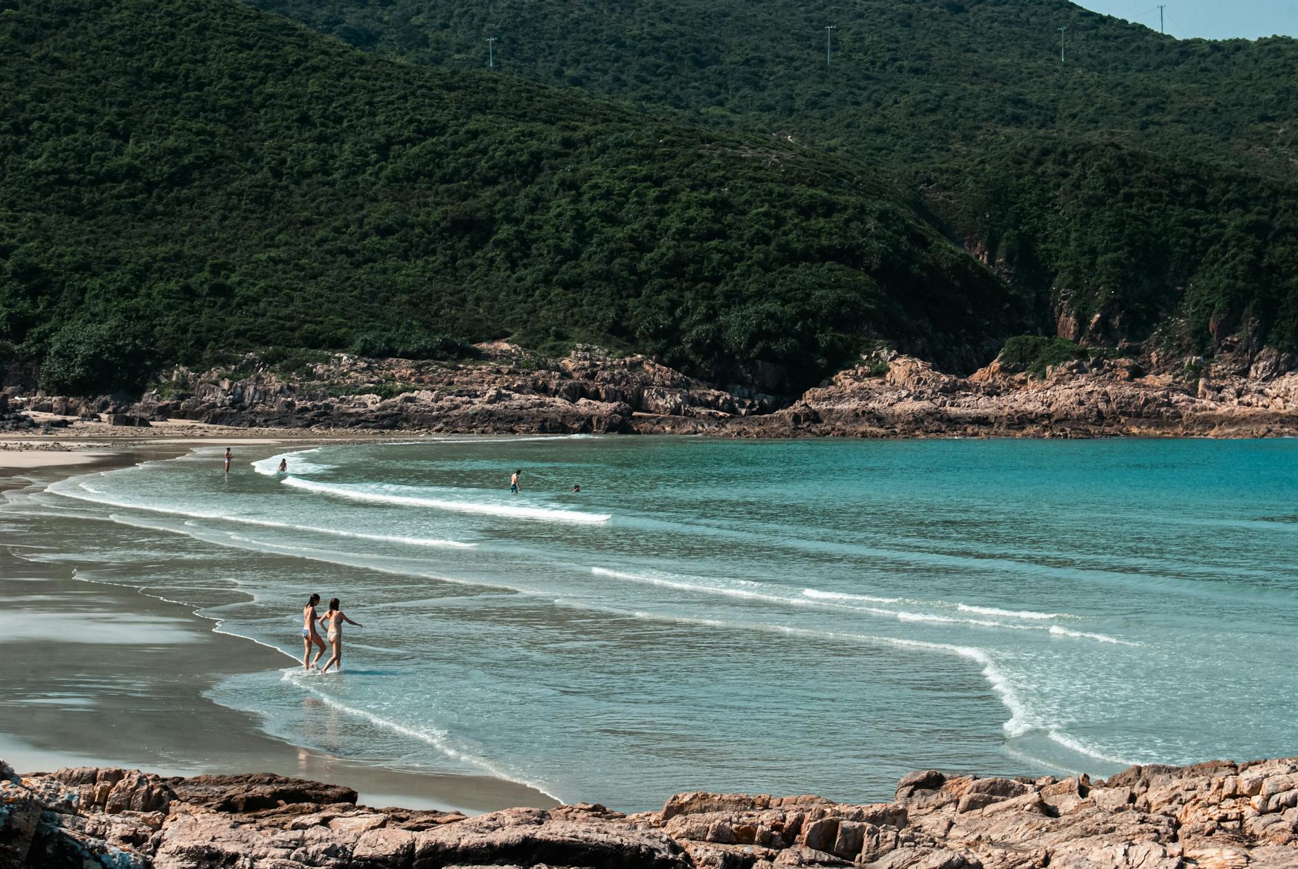 Peaceful summer day at a serene beach with swimmers enjoying the waves.