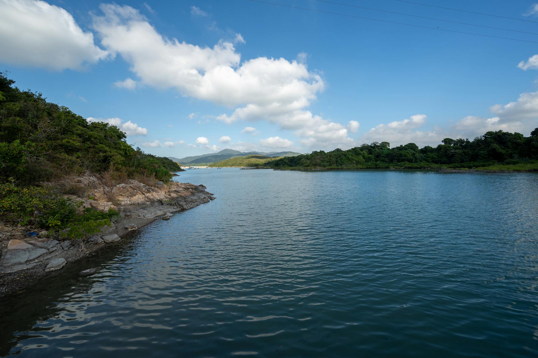 A serene view of Sai Kung's tranquil waters with lush greenery and clear blue skies.