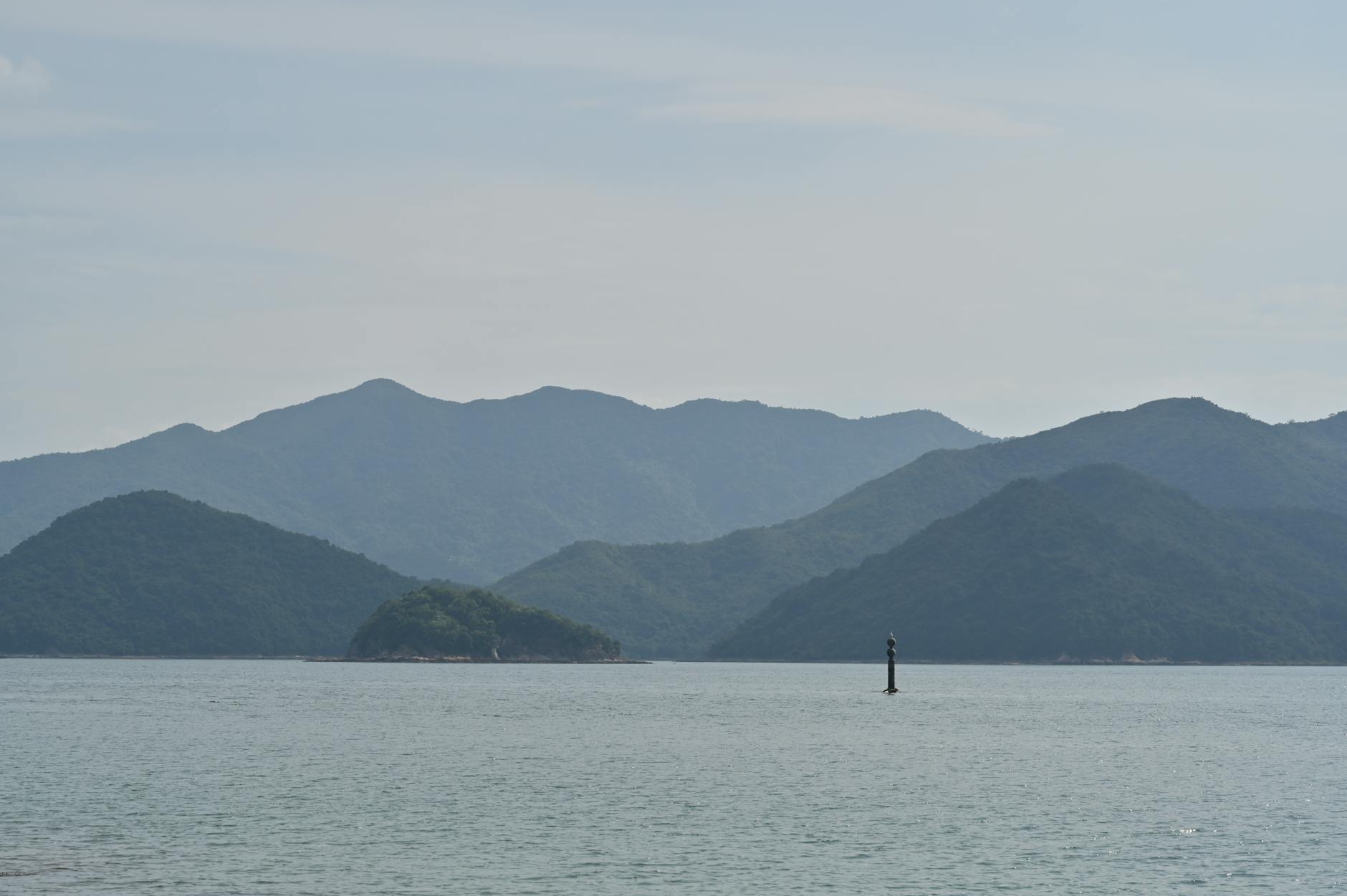 Calm sea with silhouetted mountains in Sai Kung, offering a tranquil scenic view.
